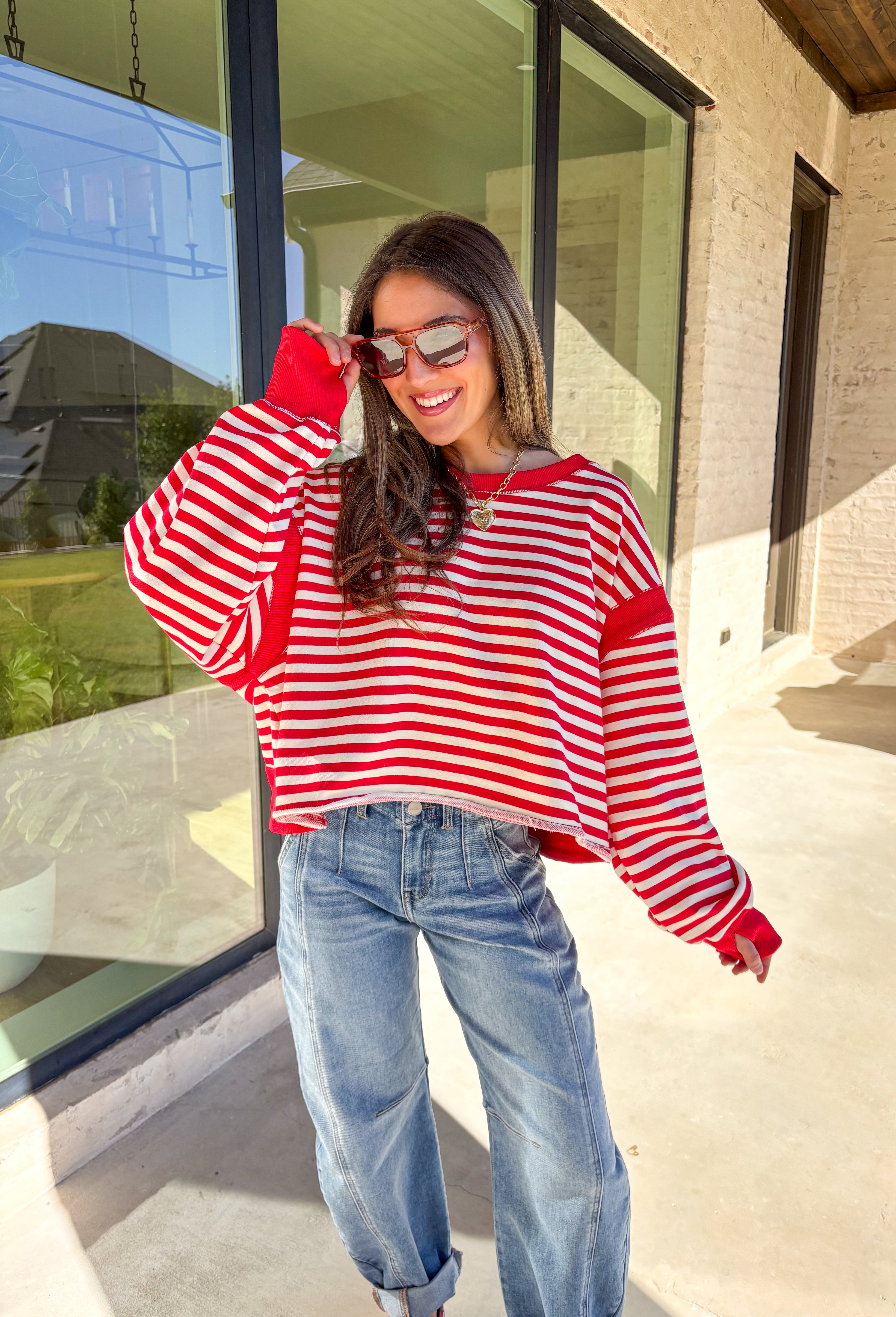A classic stripe with a flirty twist—this red and ivory long sleeve top by Rae Mode is perfect for cozy yet stylish days. The open-back design adds a fun surprise, while the solid red detailing on the cuffs, sleeve centers, and neckline gives it a bold pop. Crafted from a soft, stretchy fabric blend, it’s the ultimate mix of comfort and statement style for the season.