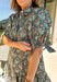 Embrace the beauty of the season in this charming dress from Entro. Featuring a gorgeous floral print in shades of hunter green, muted green, peach, and brown, this feminine dress is perfect for everything from weekend brunches to seasonal celebrations. The button-front design and flattering neckline create a timeless silhouette, while the ¾ puff sleeves with delicate tie details add a playful touch. 