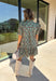 Embrace the beauty of the season in this charming dress from Entro. Featuring a gorgeous floral print in shades of hunter green, muted green, peach, and brown, this feminine dress is perfect for everything from weekend brunches to seasonal celebrations. The button-front design and flattering neckline create a timeless silhouette, while the ¾ puff sleeves with delicate tie details add a playful touch. 