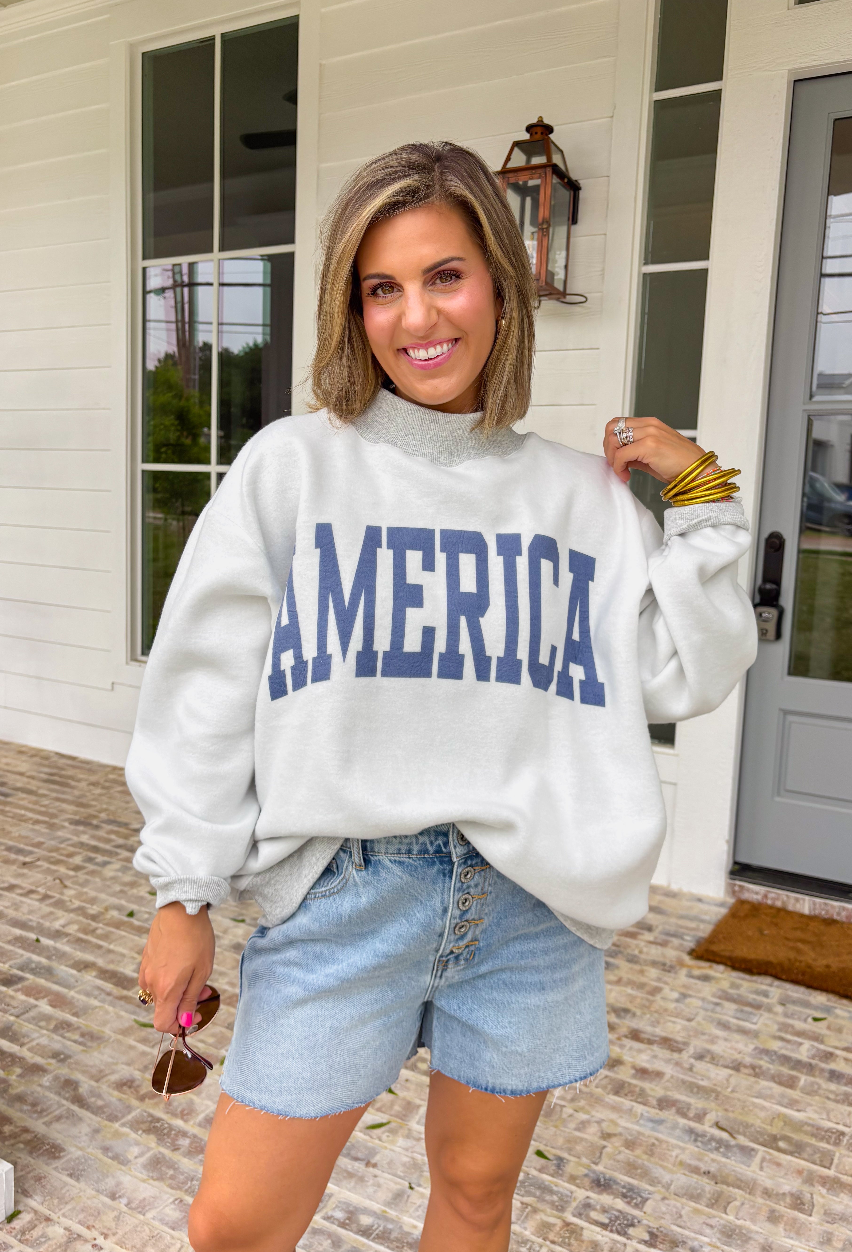 This grey reversible pullover is the ultimate cozy-meets-festive piece for your summer celebrations! Designed with two looks in one, one side features “USA” in navy with a flag design, while the other side is fleece lined with “America” in blue for a softer, cozier feel. The mock neck adds an elevated touch, making it perfect for those cooler summer nights—think fireworks, lake evenings, or early morning coffee runs. It’s an easy throw-on layer that still feels fun and patriotic. 