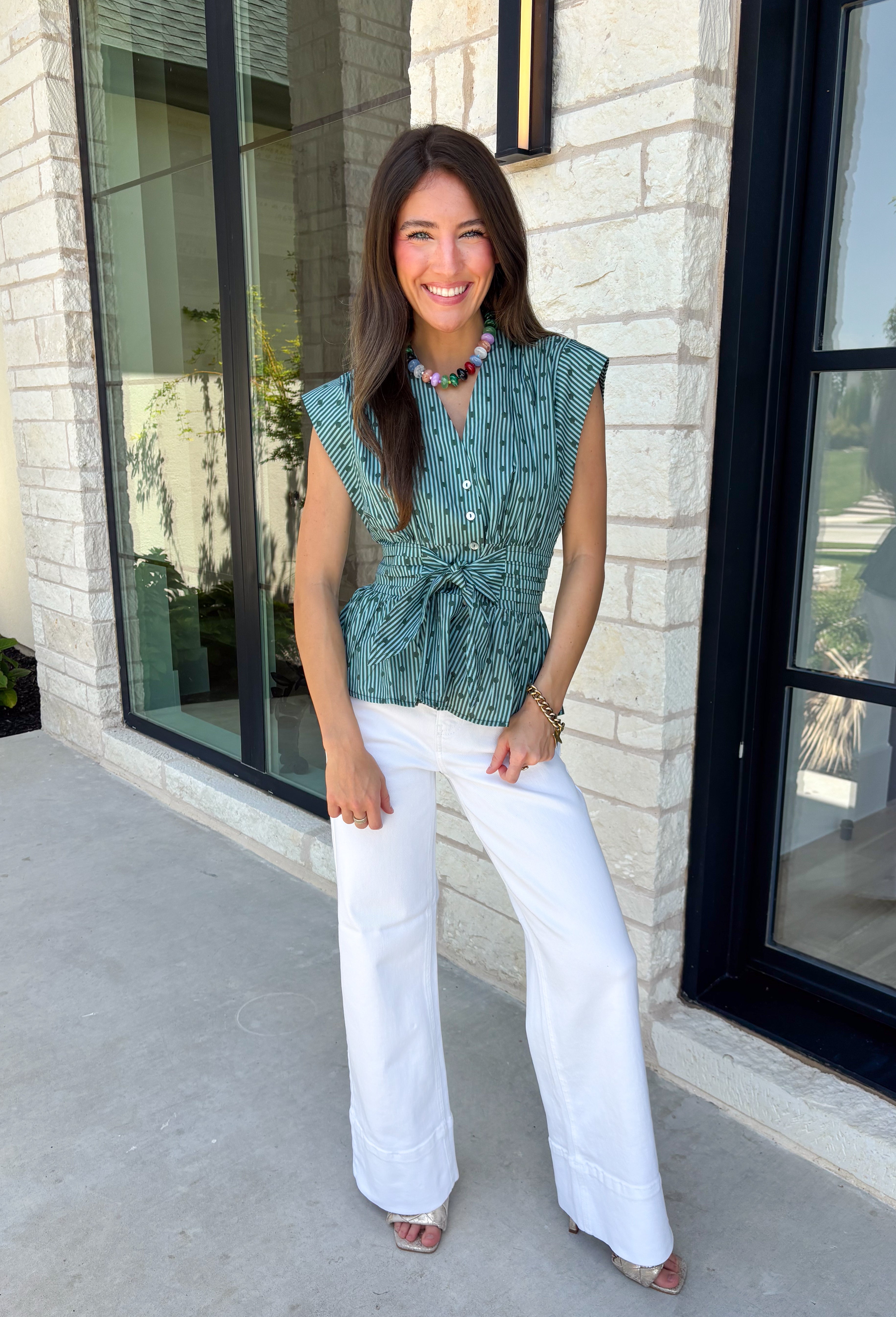 Classic stripes and flattering details make this sleeveless blouse an effortless favorite for fall! Featuring rich hunter green and light blue stripes, and hunter green polka dots, this timeless top is designed with a flattering v-neckline and an adjustable self-tie waist that creates a beautifully defined silhouette. The button front adds a polished finish, while the smocked elastic back offers all-day comfort and the perfect fit. 
