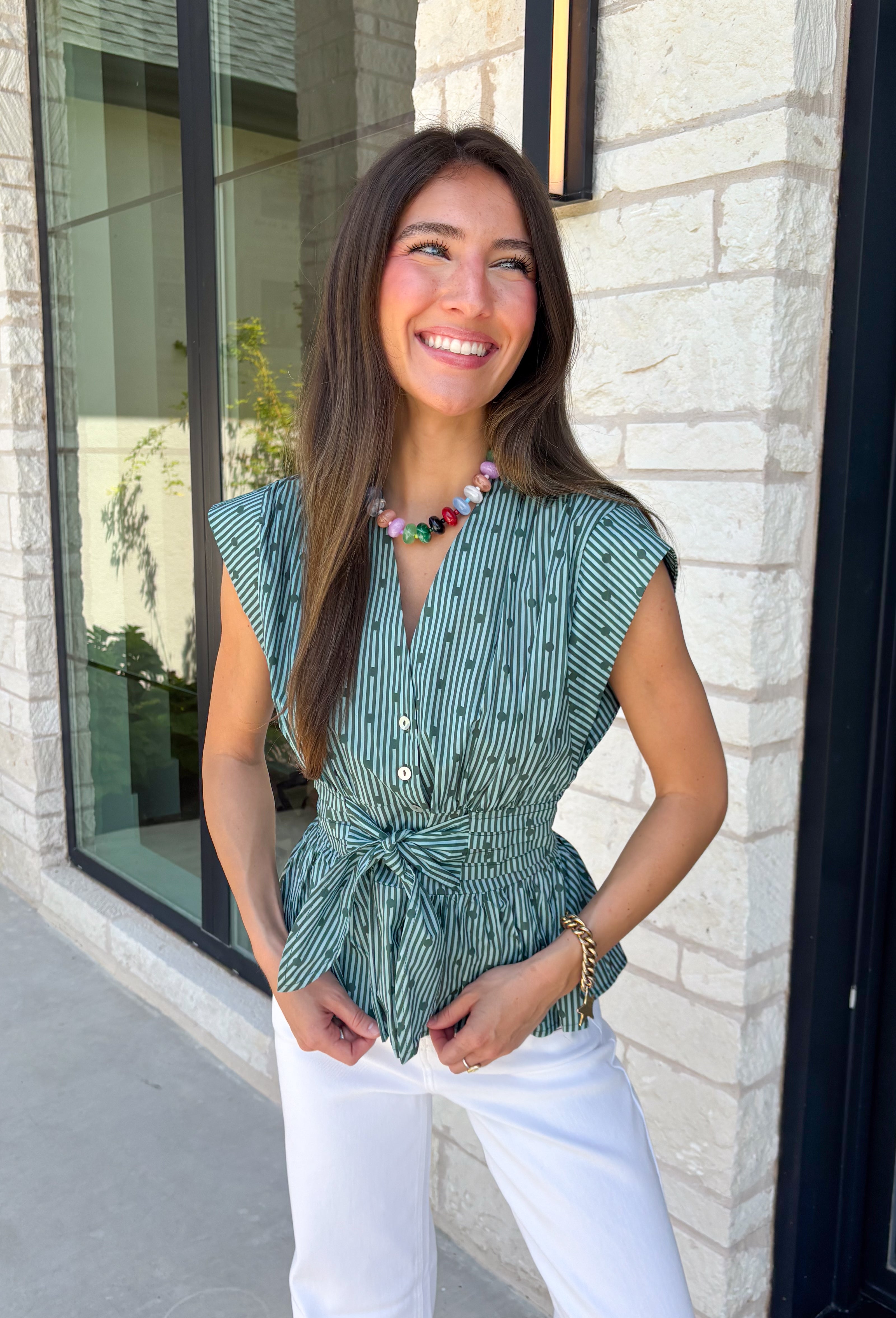 Classic stripes and flattering details make this sleeveless blouse an effortless favorite for fall! Featuring rich hunter green and light blue stripes, and hunter green polka dots, this timeless top is designed with a flattering v-neckline and an adjustable self-tie waist that creates a beautifully defined silhouette. The button front adds a polished finish, while the smocked elastic back offers all-day comfort and the perfect fit. 