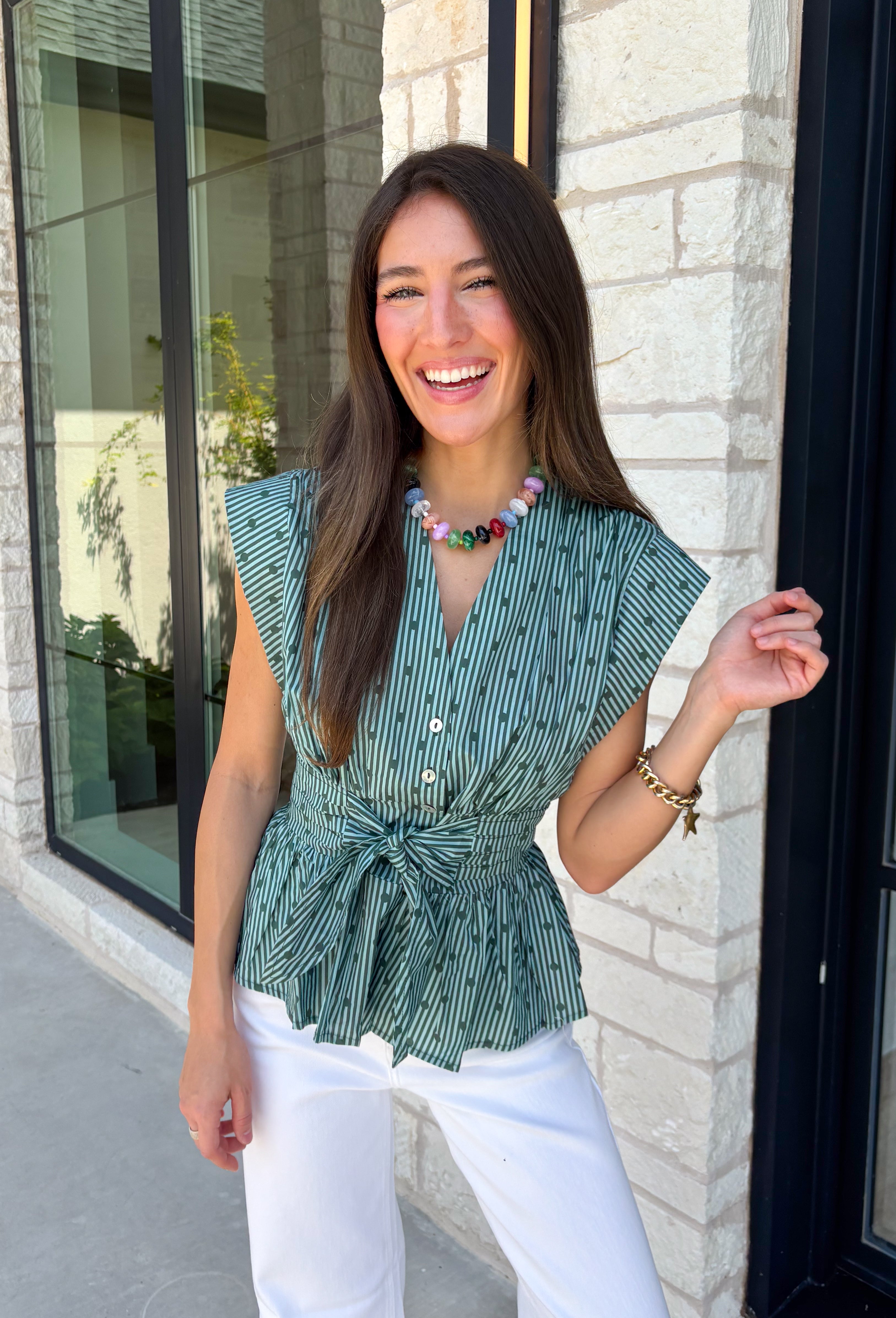 Classic stripes and flattering details make this sleeveless blouse an effortless favorite for fall! Featuring rich hunter green and light blue stripes, and hunter green polka dots, this timeless top is designed with a flattering v-neckline and an adjustable self-tie waist that creates a beautifully defined silhouette. The button front adds a polished finish, while the smocked elastic back offers all-day comfort and the perfect fit. 