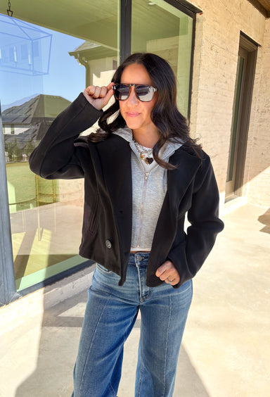 Layered and cozy, this cropped peacoat jacket by Iris brings together the best of both worlds—a timeless wool-inspired peacoat look with a built-in gray hoodie insert for casual comfort. The double-breasted front adds classic structure, while the soft gray hood gives it a relaxed, everyday twist. With side pockets and a cropped length, it’s the perfect piece for adding a cozy, layered touch to your winter outfits.