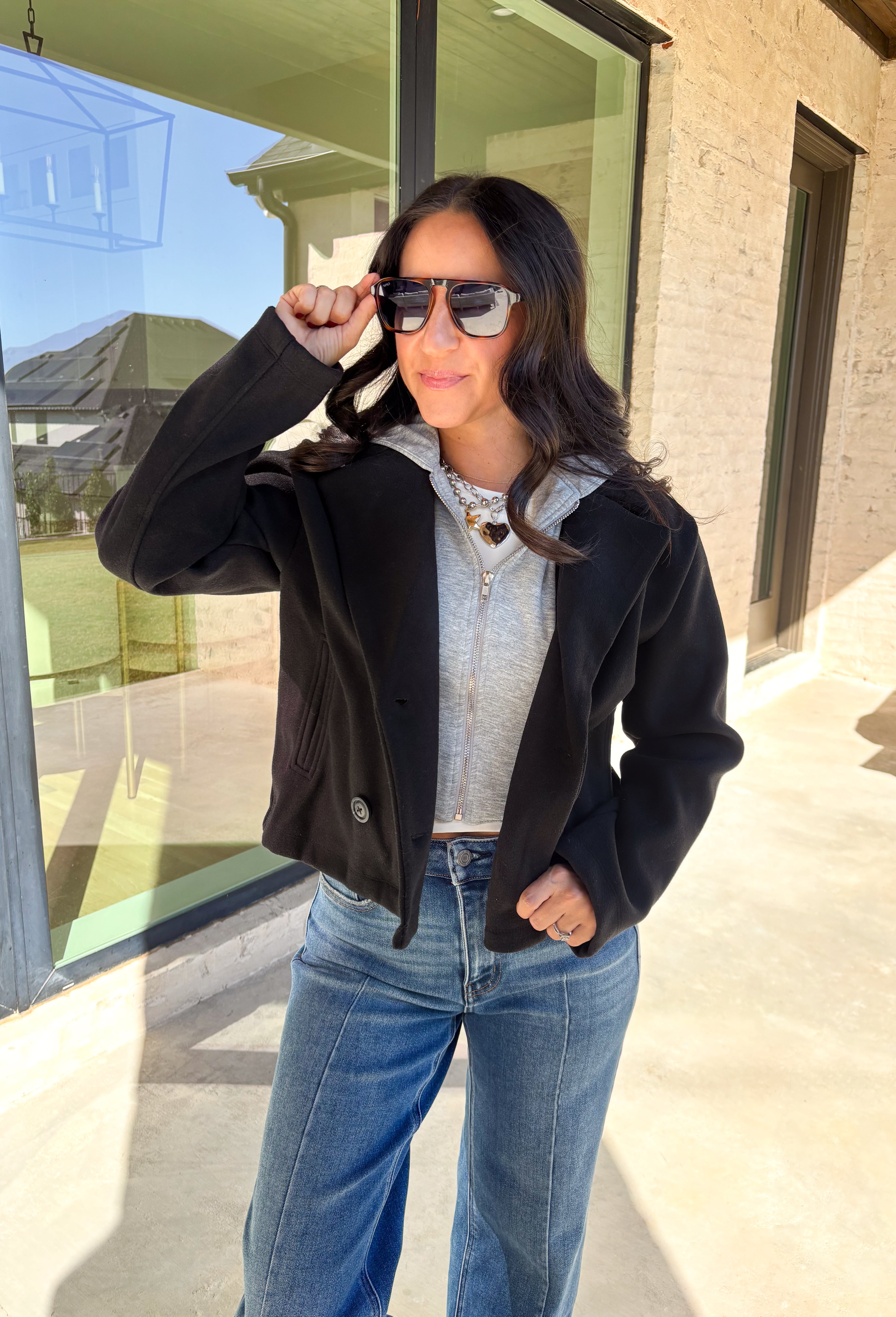 Layered and cozy, this cropped peacoat jacket by Iris brings together the best of both worlds—a timeless wool-inspired peacoat look with a built-in gray hoodie insert for casual comfort. The double-breasted front adds classic structure, while the soft gray hood gives it a relaxed, everyday twist. With side pockets and a cropped length, it’s the perfect piece for adding a cozy, layered touch to your winter outfits.