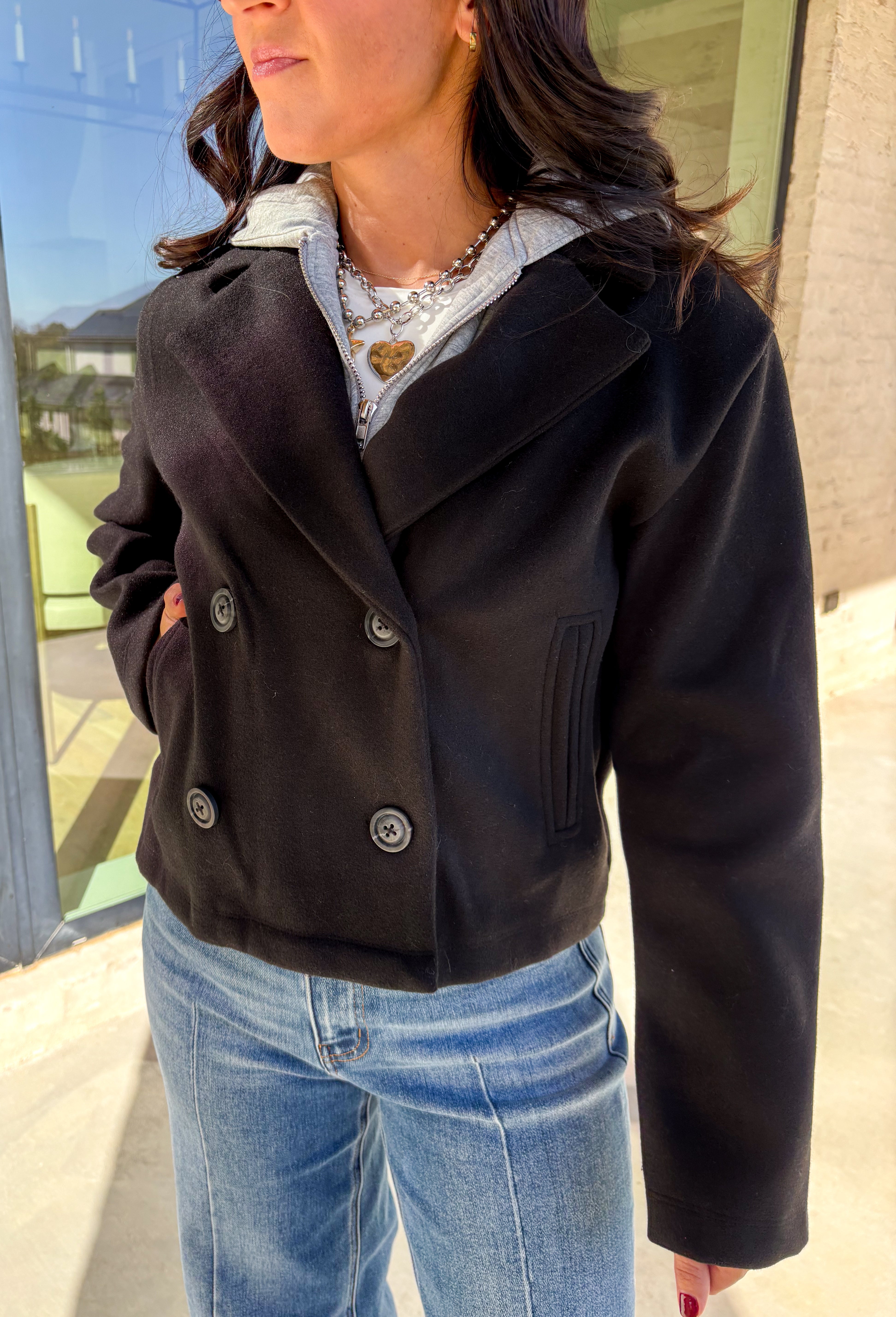 Layered and cozy, this cropped peacoat jacket by Iris brings together the best of both worlds—a timeless wool-inspired peacoat look with a built-in gray hoodie insert for casual comfort. The double-breasted front adds classic structure, while the soft gray hood gives it a relaxed, everyday twist. With side pockets and a cropped length, it’s the perfect piece for adding a cozy, layered touch to your winter outfits.