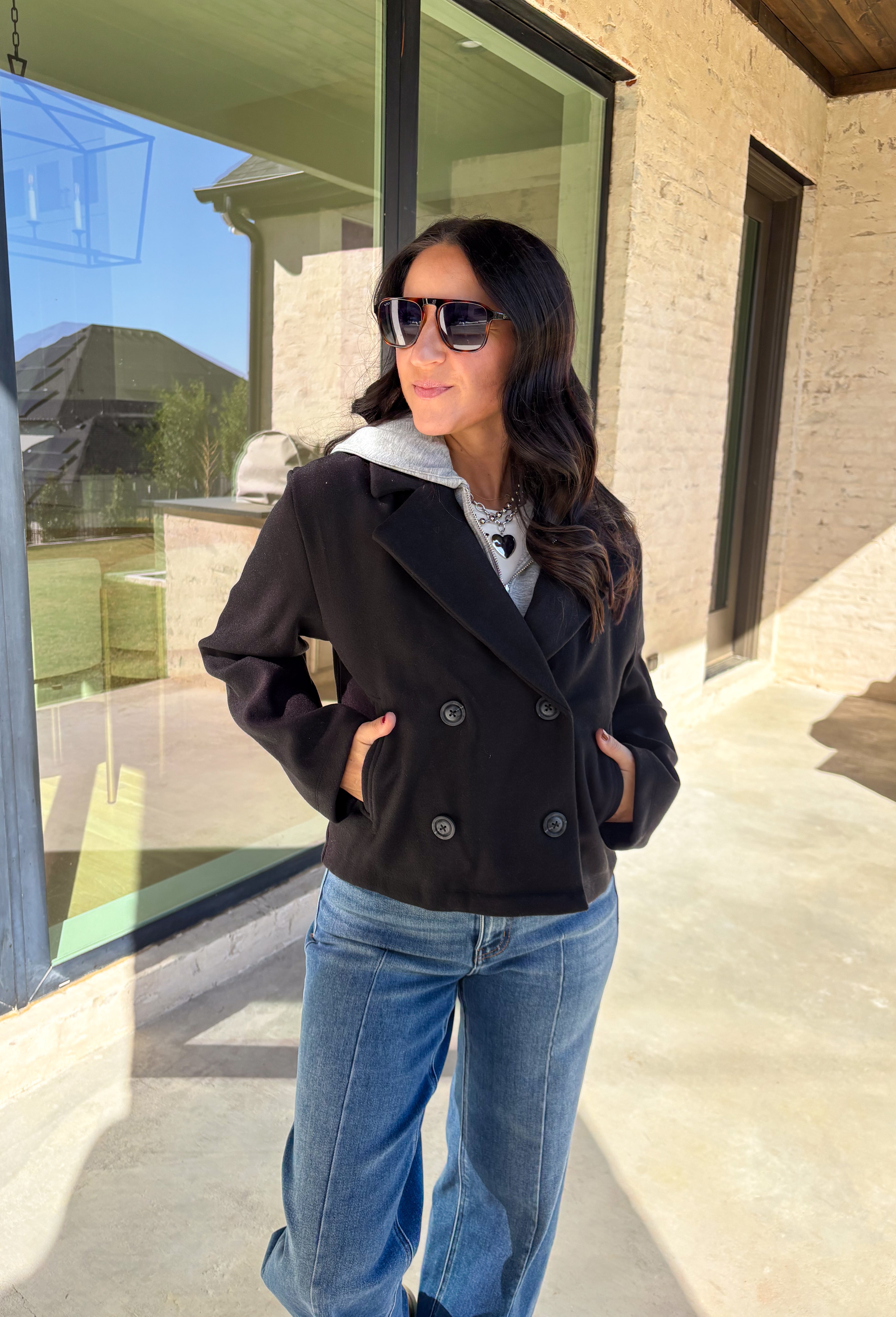 Layered and cozy, this cropped peacoat jacket by Iris brings together the best of both worlds—a timeless wool-inspired peacoat look with a built-in gray hoodie insert for casual comfort. The double-breasted front adds classic structure, while the soft gray hood gives it a relaxed, everyday twist. With side pockets and a cropped length, it’s the perfect piece for adding a cozy, layered touch to your winter outfits.