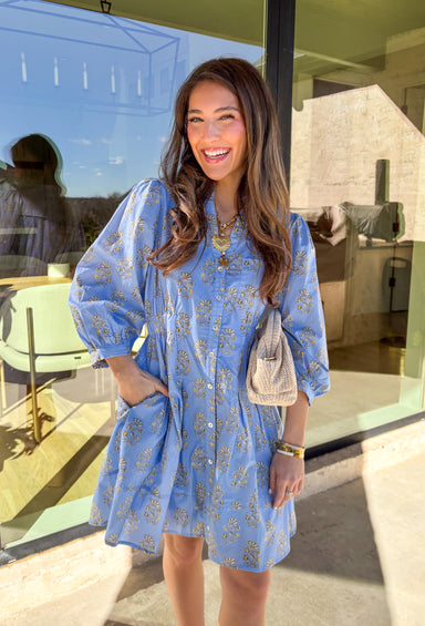 Soft, feminine, and made for spring days, this light blue long sleeve dress by Entro is the kind of piece you’ll reach for when you want to feel effortlessly put together. Featuring a floral print throughout, it brings a fresh pop of color while still feeling classic and easy to wear. Smocking at the waist creates a flattering shape without sacrificing comfort, and the front pocket detail adds a casual, laid-back touch. Finished with side pockets and a fully lined cotton feel, this dress is perfect for brun