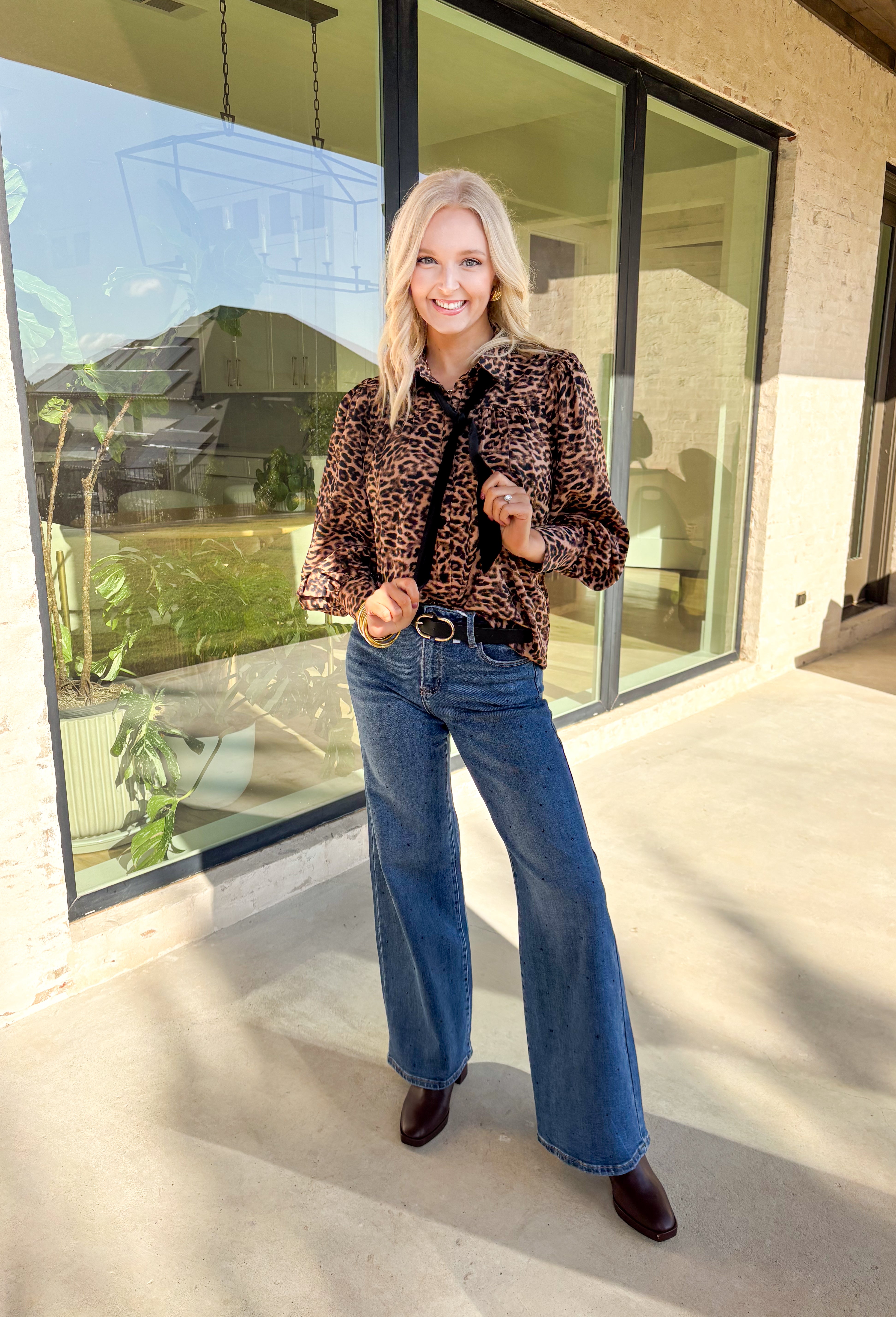 Make a statement this holiday season in this stunning leopard satin top by Fate. Designed with a button-down front and collared neckline, this piece brings a touch of luxe shine to your winter wardrobe. The black velvet bow detail at the top adds a festive finish, making it perfect for parties, dinners, or any occasion that calls for a little extra flair.