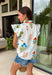 This floral top is bursting with fresh summer charm. Featuring a colorful floral print in shades of blue, green, and orange, it brings the perfect pop of color to your everyday wardrobe. The flutter sleeves add a soft, feminine touch, while the pleated band collar and v-neckline create a polished look that's easy to dress up or down. The orange scallop trim adds the sweetest finishing detail, making this top truly stand out. Lightweight and breathable in 100% cotton.
