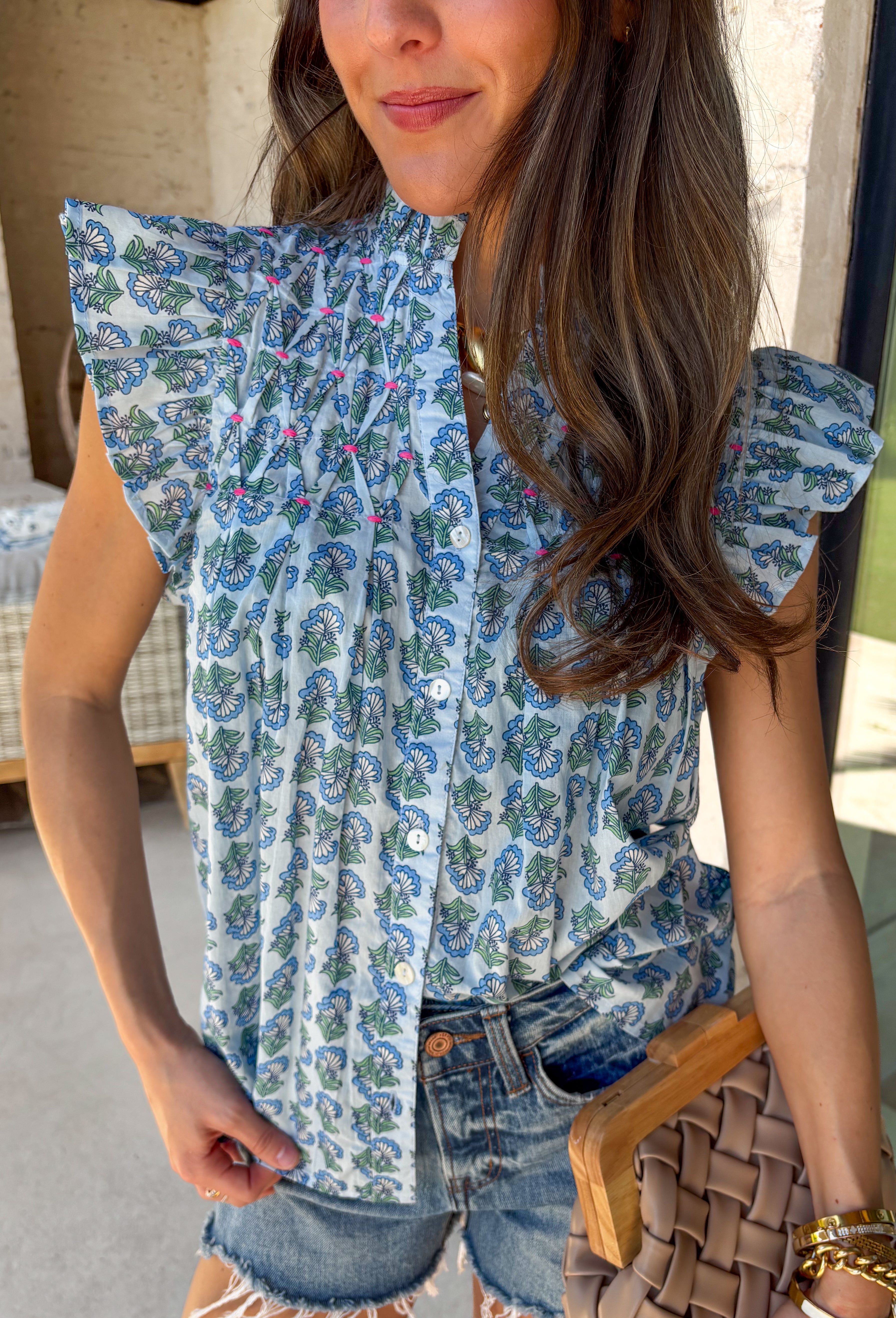 This light blue floral top is such a fresh, feminine pick for summer! The soft blue base paired with delicate floral print and pink embroidered pleating creates the prettiest, eye-catching detail that feels both playful and polished. The ruffle sleeves add a light, breezy touch, making it perfect for warm days when you still want something a little elevated. Made from breathable cotton, it’s easy to wear from casual outings to lunch plans or even a dressed-up moment. 