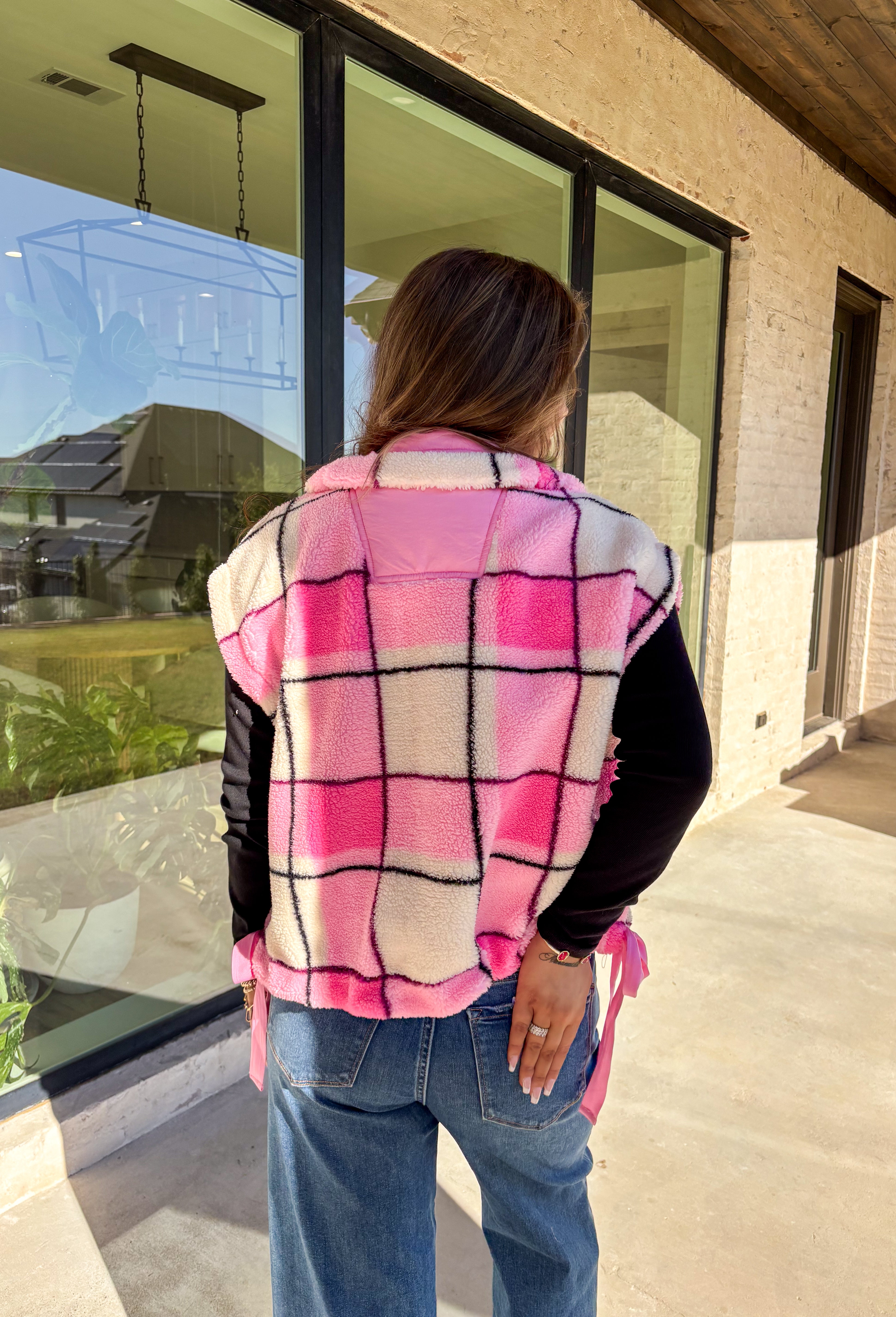 Get bundled up in cuteness with this cozy pink and white plaid vest! With sweet pops of black in the pattern and darling pink bow ties on each side, it brings just the right amount of charm to your cold-weather wardrobe. Whether you're layering it over a long sleeve tee or a chunky knit sweater, this vest is ready to warm things up in the coziest way.
