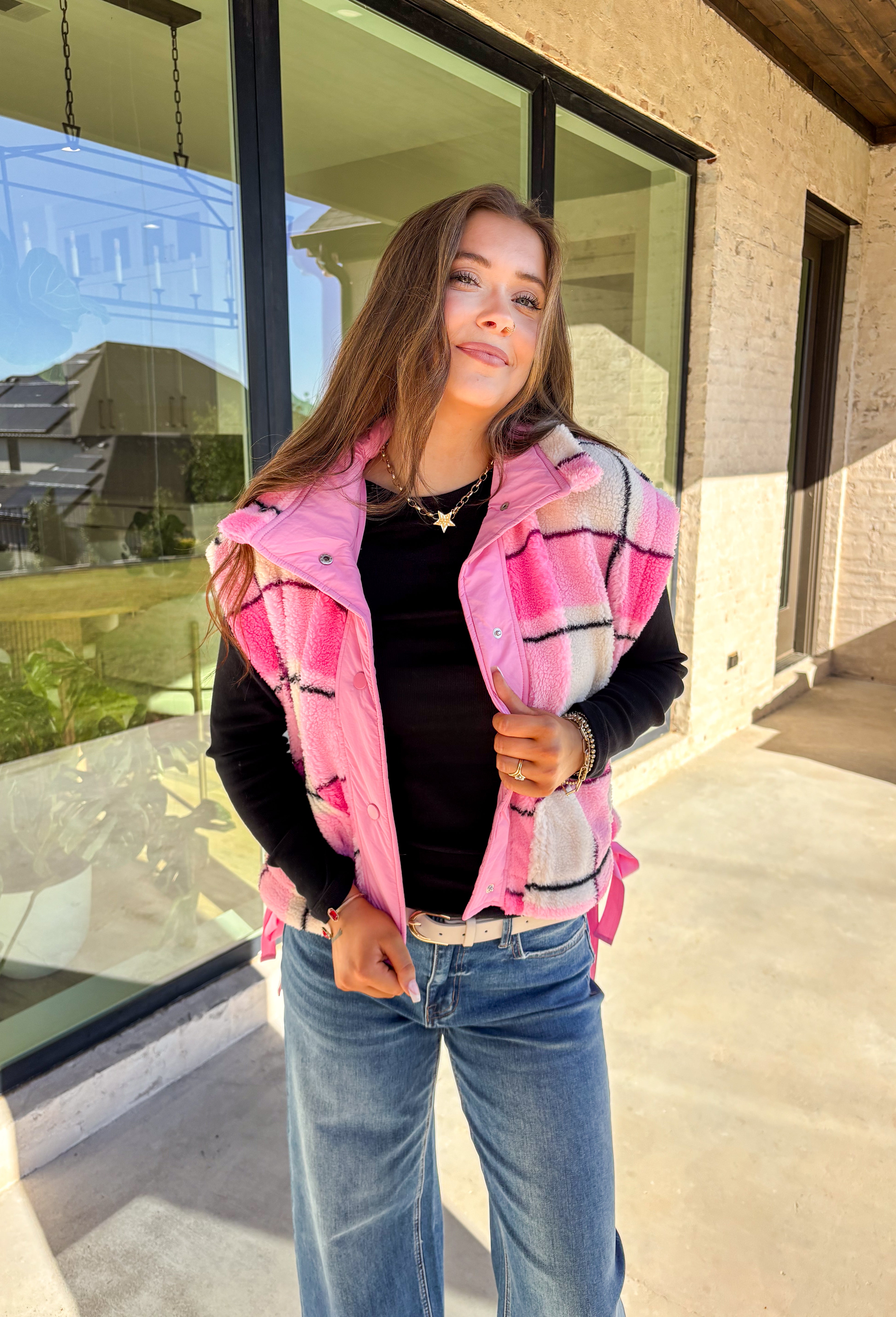 Get bundled up in cuteness with this cozy pink and white plaid vest! With sweet pops of black in the pattern and darling pink bow ties on each side, it brings just the right amount of charm to your cold-weather wardrobe. Whether you're layering it over a long sleeve tee or a chunky knit sweater, this vest is ready to warm things up in the coziest way.