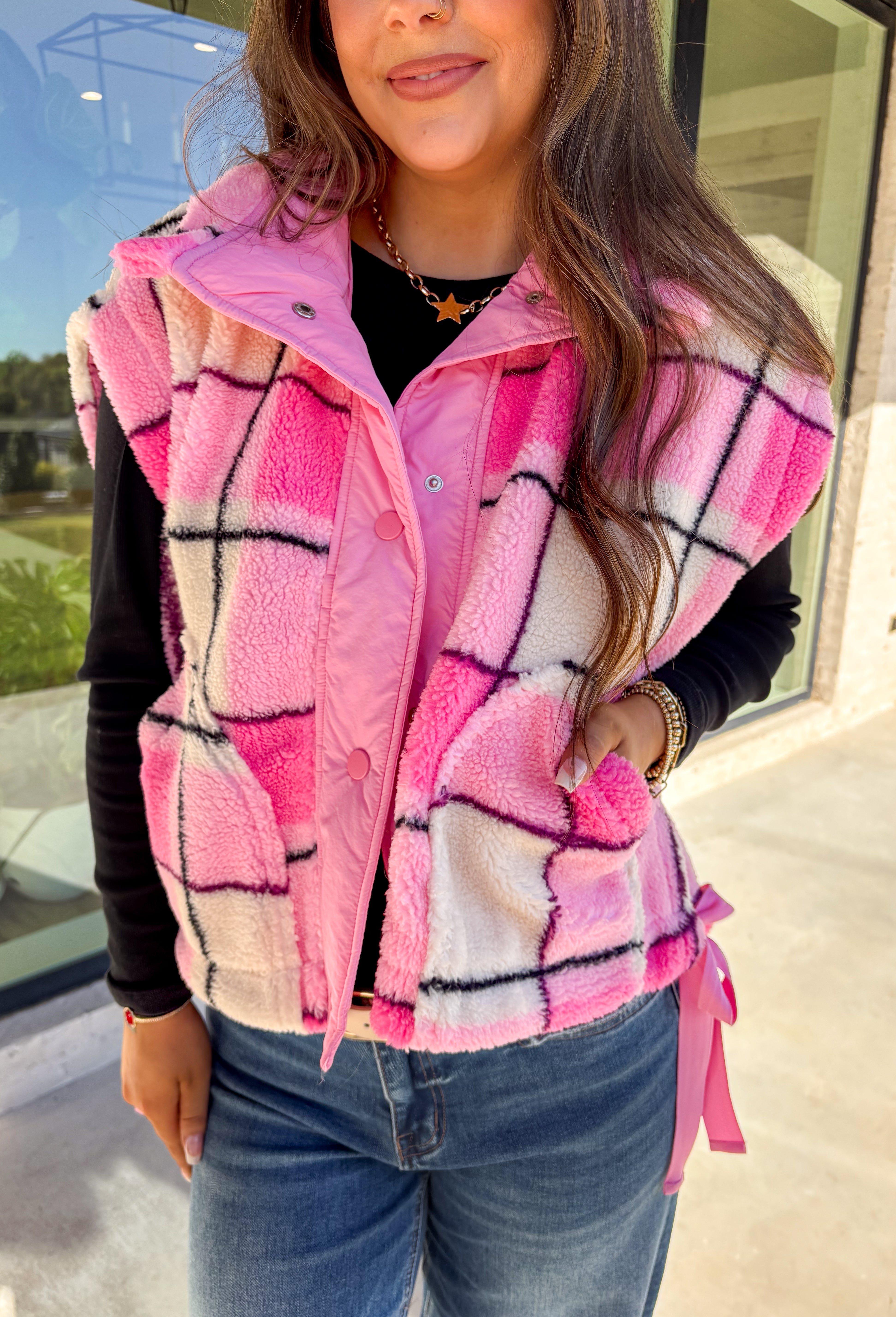 Get bundled up in cuteness with this cozy pink and white plaid vest! With sweet pops of black in the pattern and darling pink bow ties on each side, it brings just the right amount of charm to your cold-weather wardrobe. Whether you're layering it over a long sleeve tee or a chunky knit sweater, this vest is ready to warm things up in the coziest way.