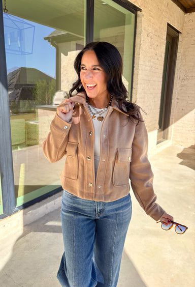 A timeless staple with everyday versatility, this light taupe jacket by Blashe is perfect for layering through the season. Designed with a collared neckline, silver snap button closures, and two front pockets, it balances utility with modern style. Lightweight yet cozy, it’s an easy throw-on piece that works just as well over dresses as it does with denim.