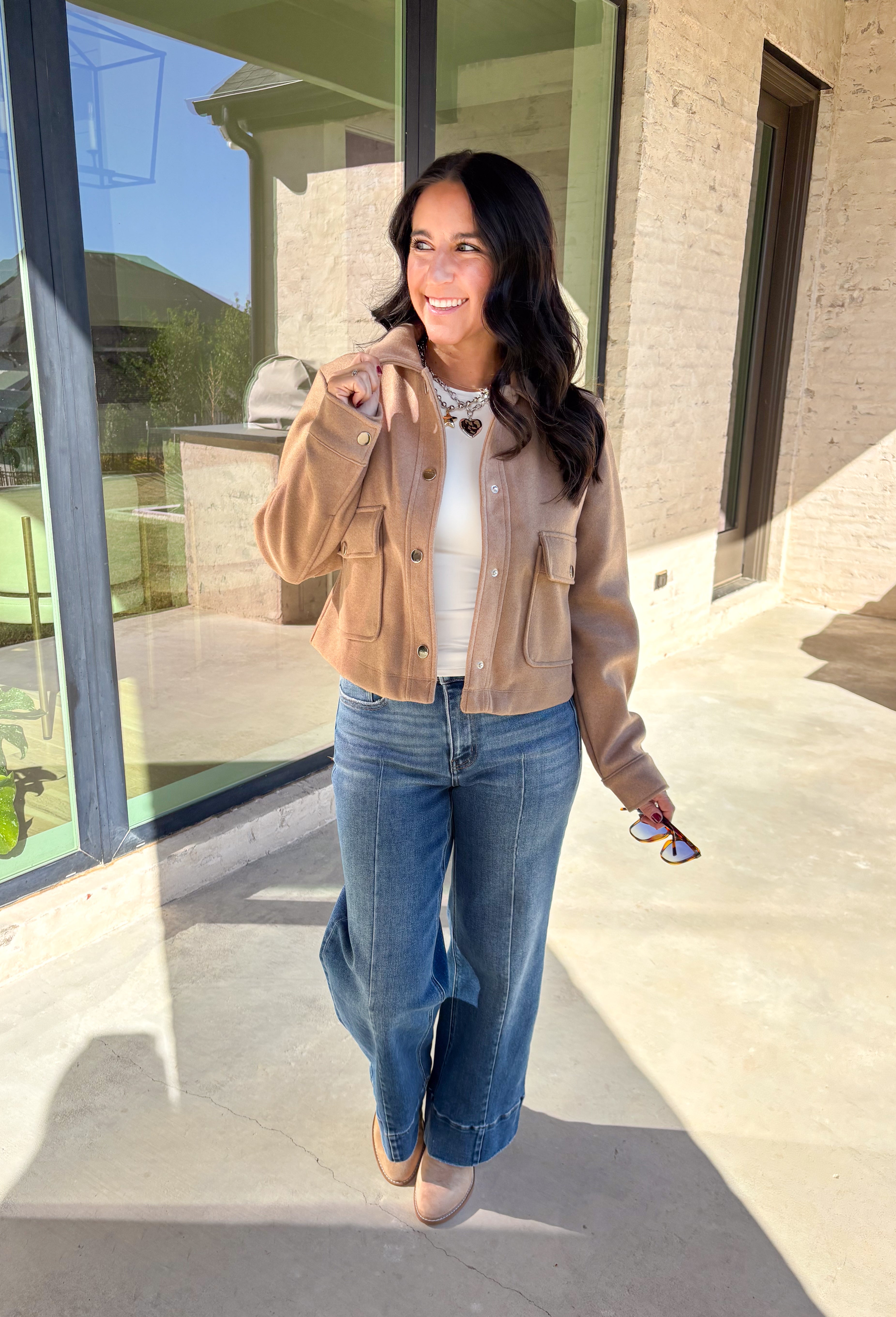 A timeless staple with everyday versatility, this light taupe jacket by Blashe is perfect for layering through the season. Designed with a collared neckline, silver snap button closures, and two front pockets, it balances utility with modern style. Lightweight yet cozy, it’s an easy throw-on piece that works just as well over dresses as it does with denim.