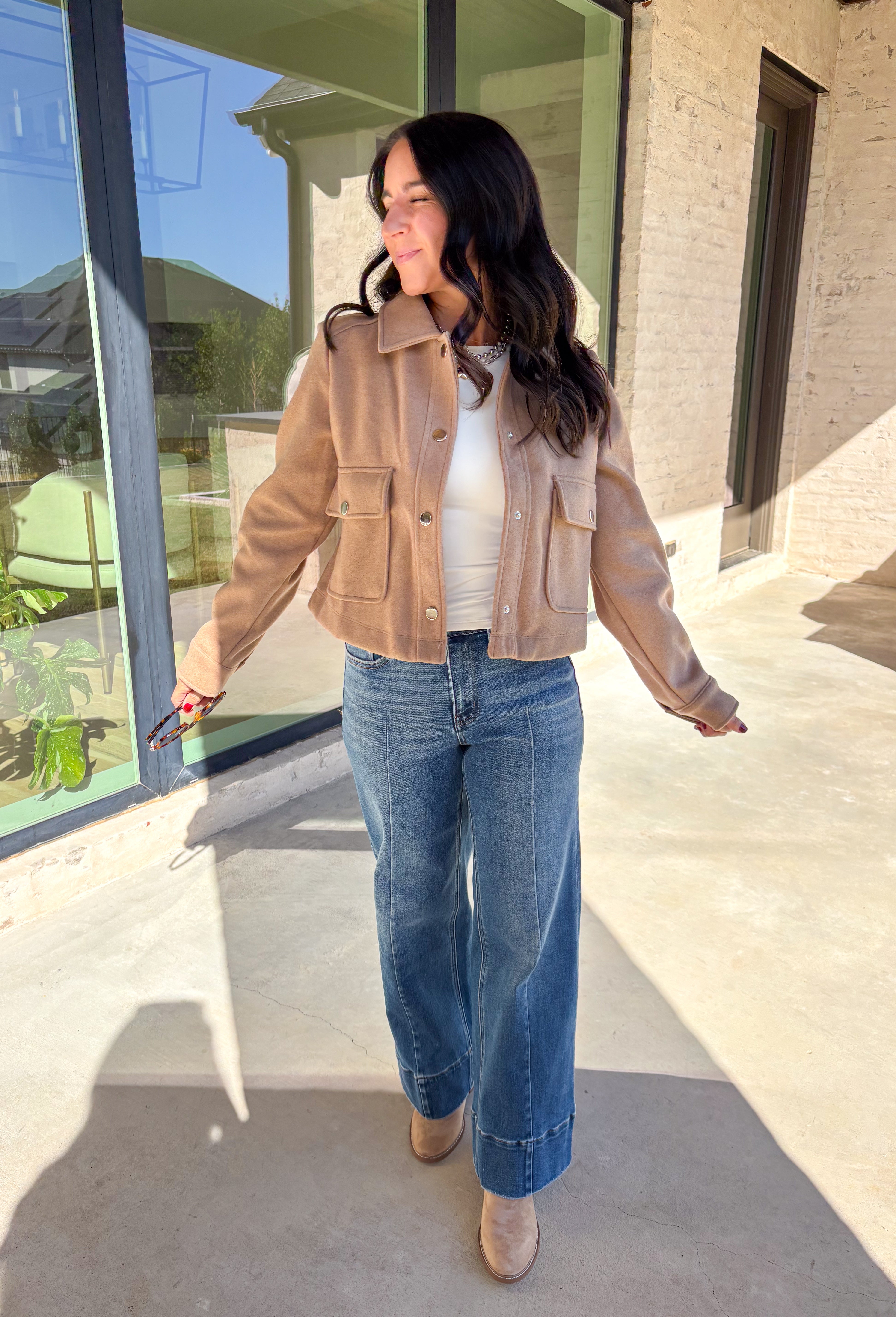 A timeless staple with everyday versatility, this light taupe jacket by Blashe is perfect for layering through the season. Designed with a collared neckline, silver snap button closures, and two front pockets, it balances utility with modern style. Lightweight yet cozy, it’s an easy throw-on piece that works just as well over dresses as it does with denim.