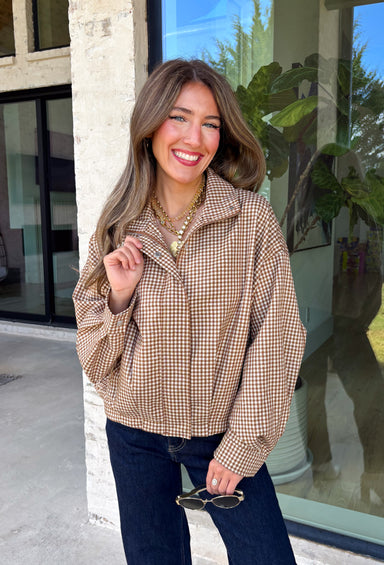 Classic gingham gets a fun fall refresh with this camel and cream jacket from Glam. The neutral checkered print keeps it easy to style, while sequin stitching throughout adds just the right amount of sparkle when it catches the light. A collared neckline and both zipper and button closures give it a structured, jacket-inspired look, while the elastic back hem creates a comfortable shape.