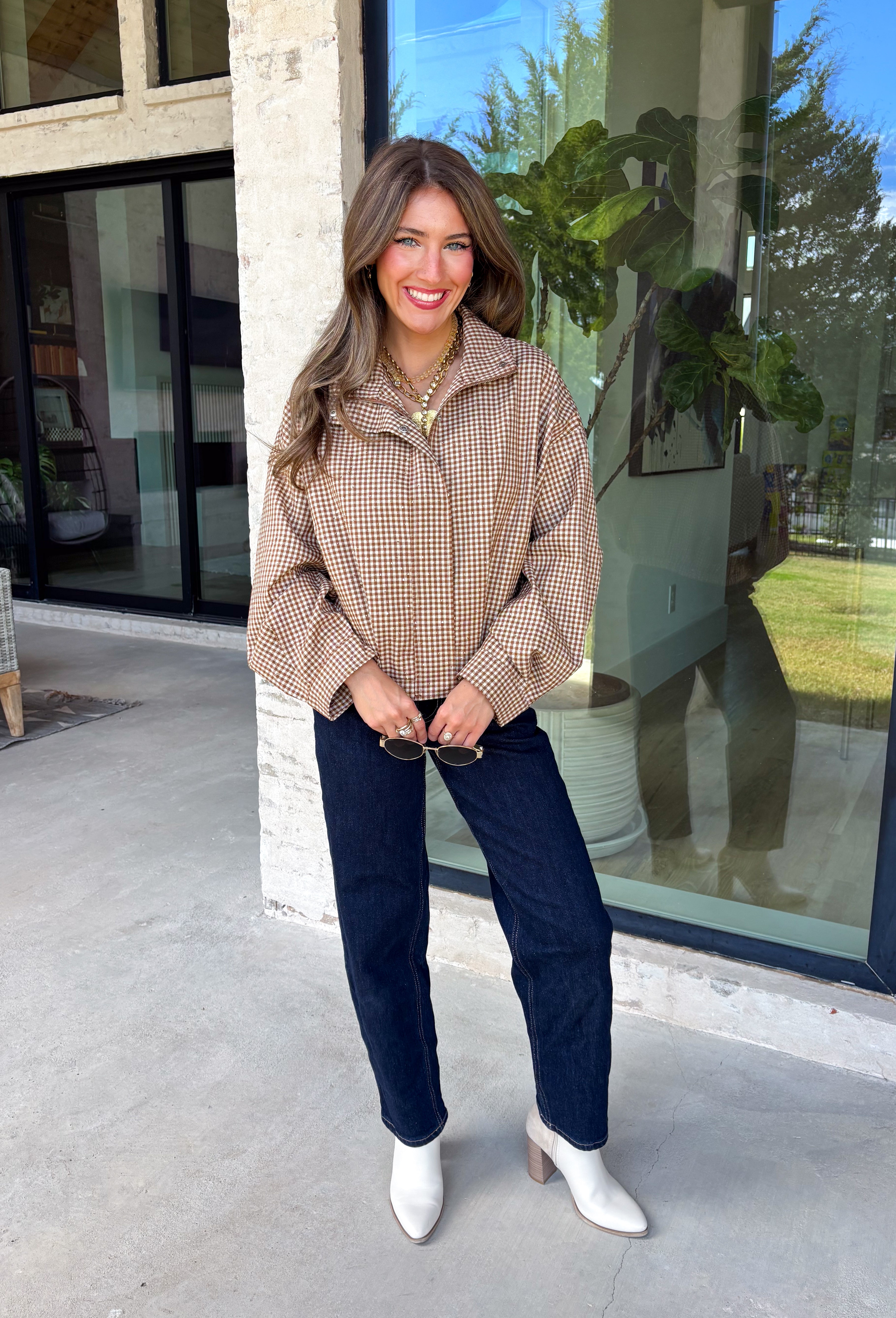 Classic gingham gets a fun fall refresh with this camel and cream jacket from Glam. The neutral checkered print keeps it easy to style, while sequin stitching throughout adds just the right amount of sparkle when it catches the light. A collared neckline and both zipper and button closures give it a structured, jacket-inspired look, while the elastic back hem creates a comfortable shape.