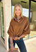 Elevate your everyday wardrobe with this effortlessly polished faux suede top from Day + Moon. Designed in a warm camel hue, this timeless button-down blouse is the perfect blend of classic style and seasonal charm. The collared neckline gives it a refined look, while the soft balloon sleeves add just the right amount of feminine flair. Crafted from buttery-soft faux suede, this versatile top easily transitions from the office to weekend outings, making it a staple you'll reach for all fall long.