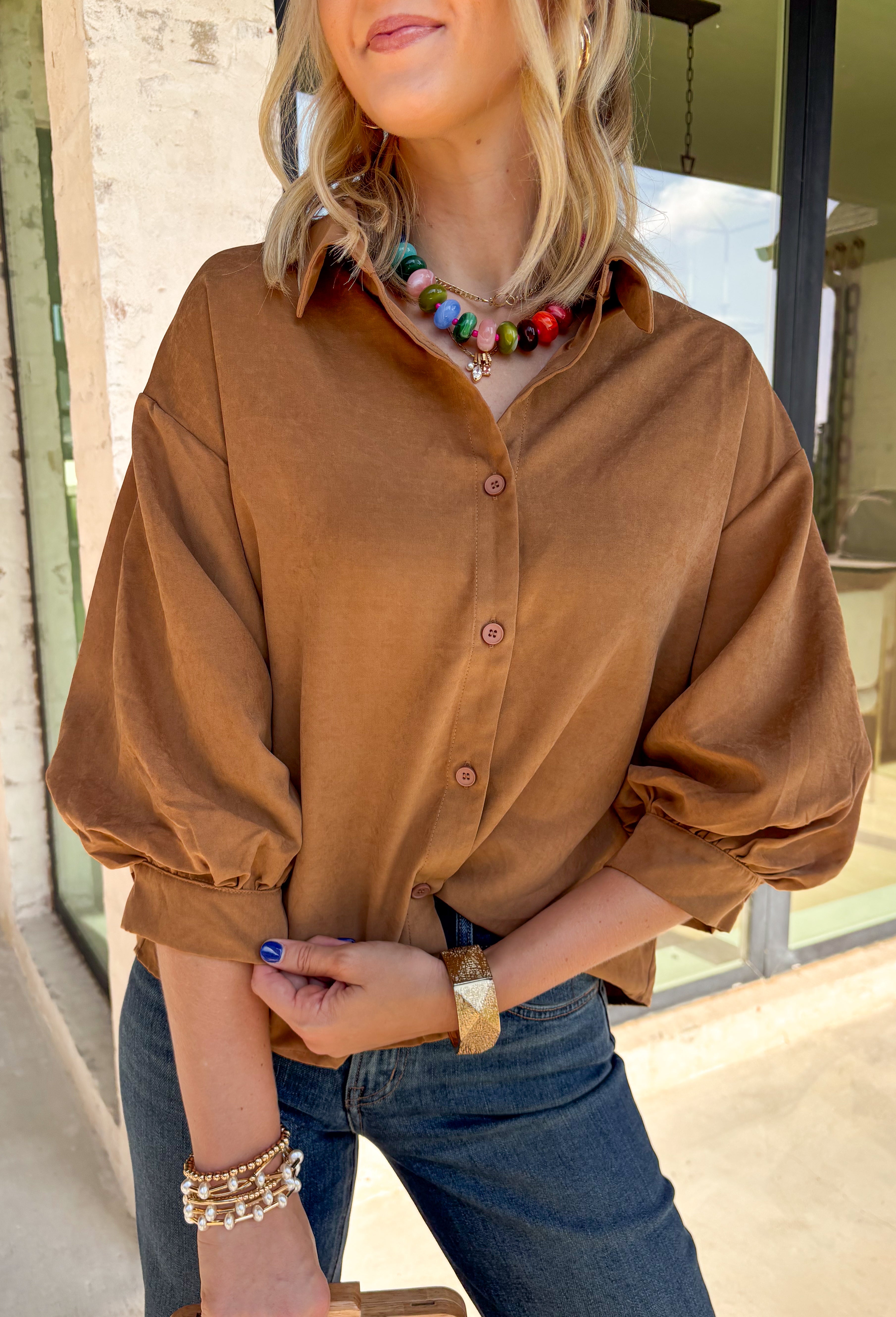 Elevate your everyday wardrobe with this effortlessly polished faux suede top from Day + Moon. Designed in a warm camel hue, this timeless button-down blouse is the perfect blend of classic style and seasonal charm. The collared neckline gives it a refined look, while the soft balloon sleeves add just the right amount of feminine flair. Crafted from buttery-soft faux suede, this versatile top easily transitions from the office to weekend outings, making it a staple you'll reach for all fall long.