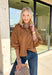 Elevate your everyday wardrobe with this effortlessly polished faux suede top from Day + Moon. Designed in a warm camel hue, this timeless button-down blouse is the perfect blend of classic style and seasonal charm. The collared neckline gives it a refined look, while the soft balloon sleeves add just the right amount of feminine flair. Crafted from buttery-soft faux suede, this versatile top easily transitions from the office to weekend outings, making it a staple you'll reach for all fall long.