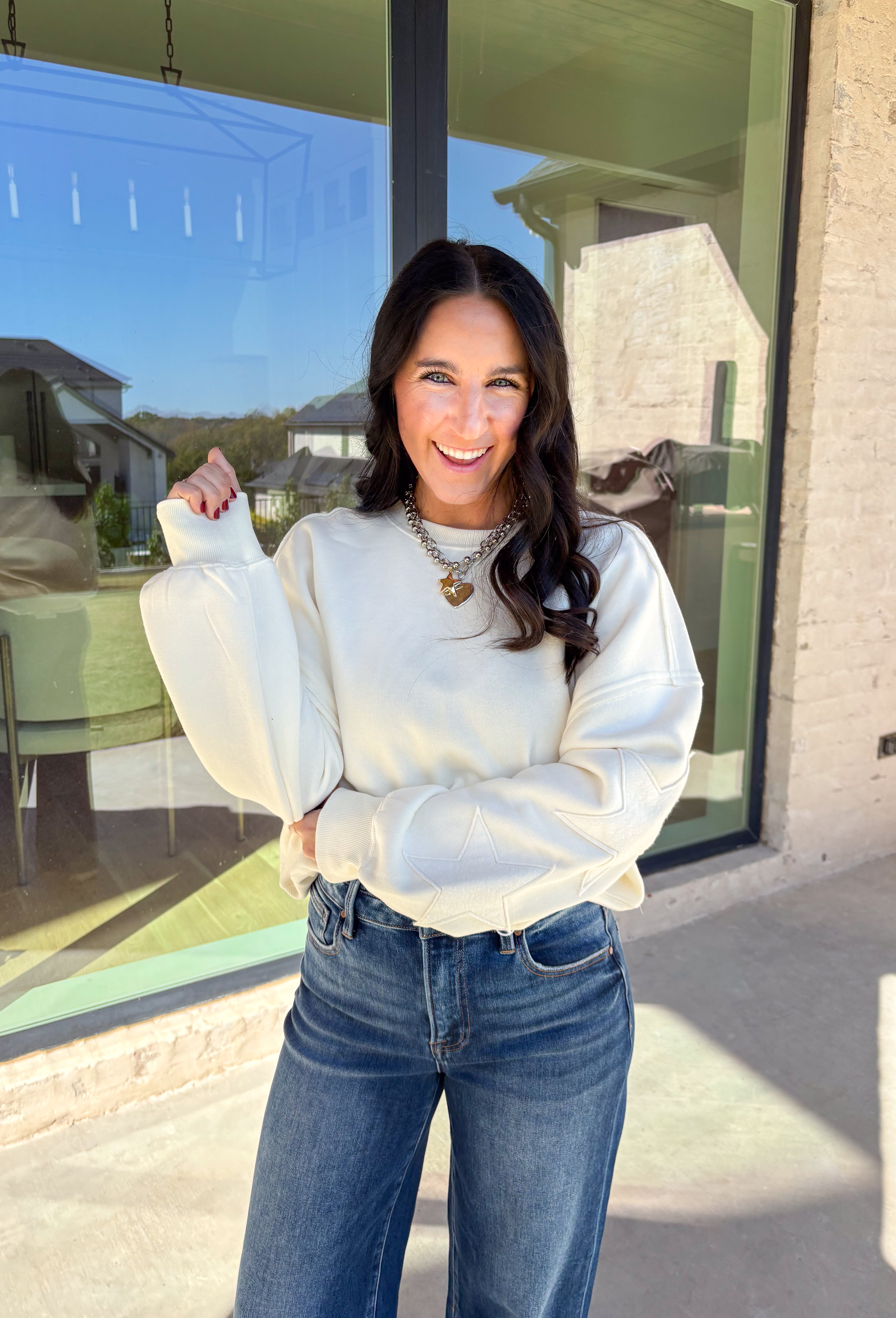 This off-white pullover by Double Zero brings cozy comfort with a touch of playful charm. Featuring two large monochromatic stars on each sleeve, this fleece-lined sweatshirt adds a fun twist to your everyday look. With its relaxed fit and ultra-soft feel, it’s the perfect grab-and-go piece for chilly days or cozy nights in.