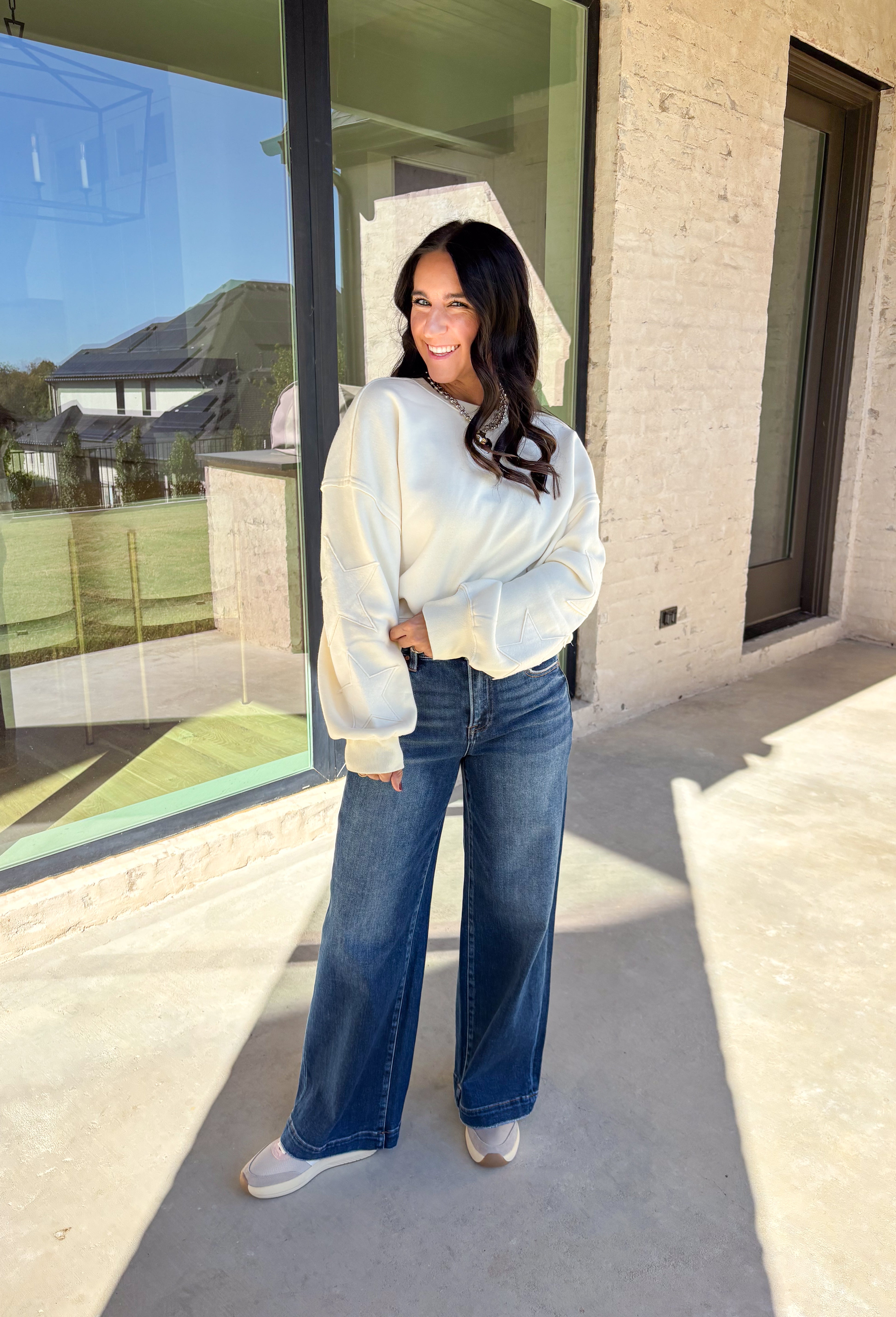 This off-white pullover by Double Zero brings cozy comfort with a touch of playful charm. Featuring two large monochromatic stars on each sleeve, this fleece-lined sweatshirt adds a fun twist to your everyday look. With its relaxed fit and ultra-soft feel, it’s the perfect grab-and-go piece for chilly days or cozy nights in.