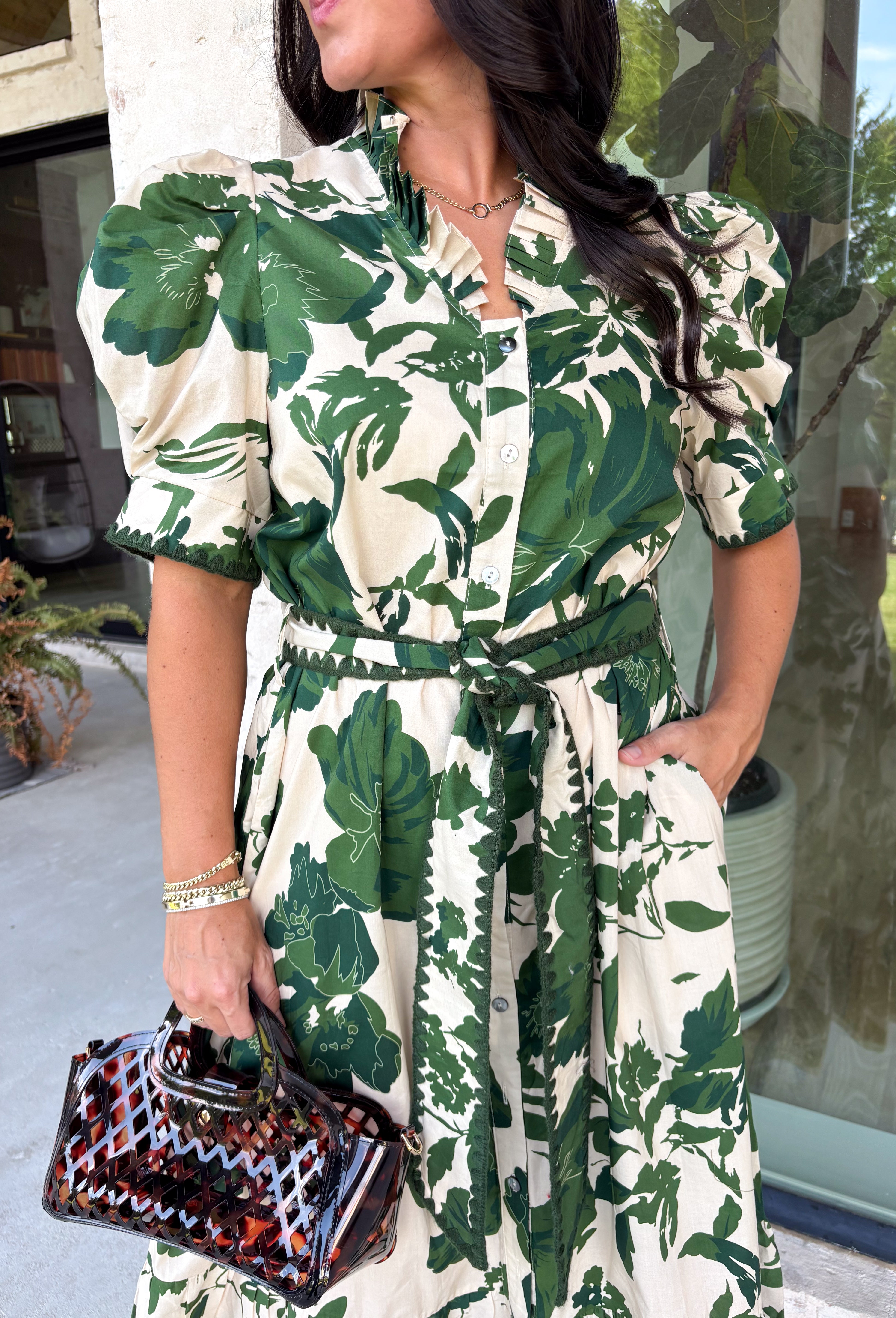 Classic florals and thoughtful details make this midi dress a standout for the season. Designed with a soft cream backdrop and an olive floral print, this beautifully feminine dress is perfect for everything from brunch dates to family gatherings. Delicate pleating along the neckline and collar adds elegant texture, while the matching self-tie belt creates a flattering, customizable silhouette. 
