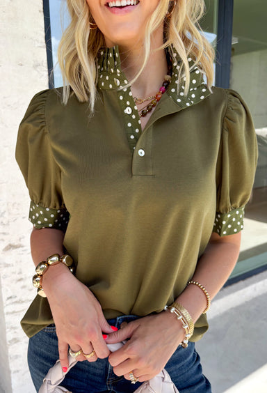 A timeless polka dot print meets feminine details in this effortlessly polished top from Entro. Designed in a rich olive hue with crisp white polka dot accents, this top is perfect for elevating your everyday wardrobe. The ruffled high neckline adds a refined touch, while the button-front closure and contrast cuffs create a beautifully tailored finish. Puff sleeves and button cuffs complete the look, making this versatile blouse an easy choice for everything from workdays to weekend outings.