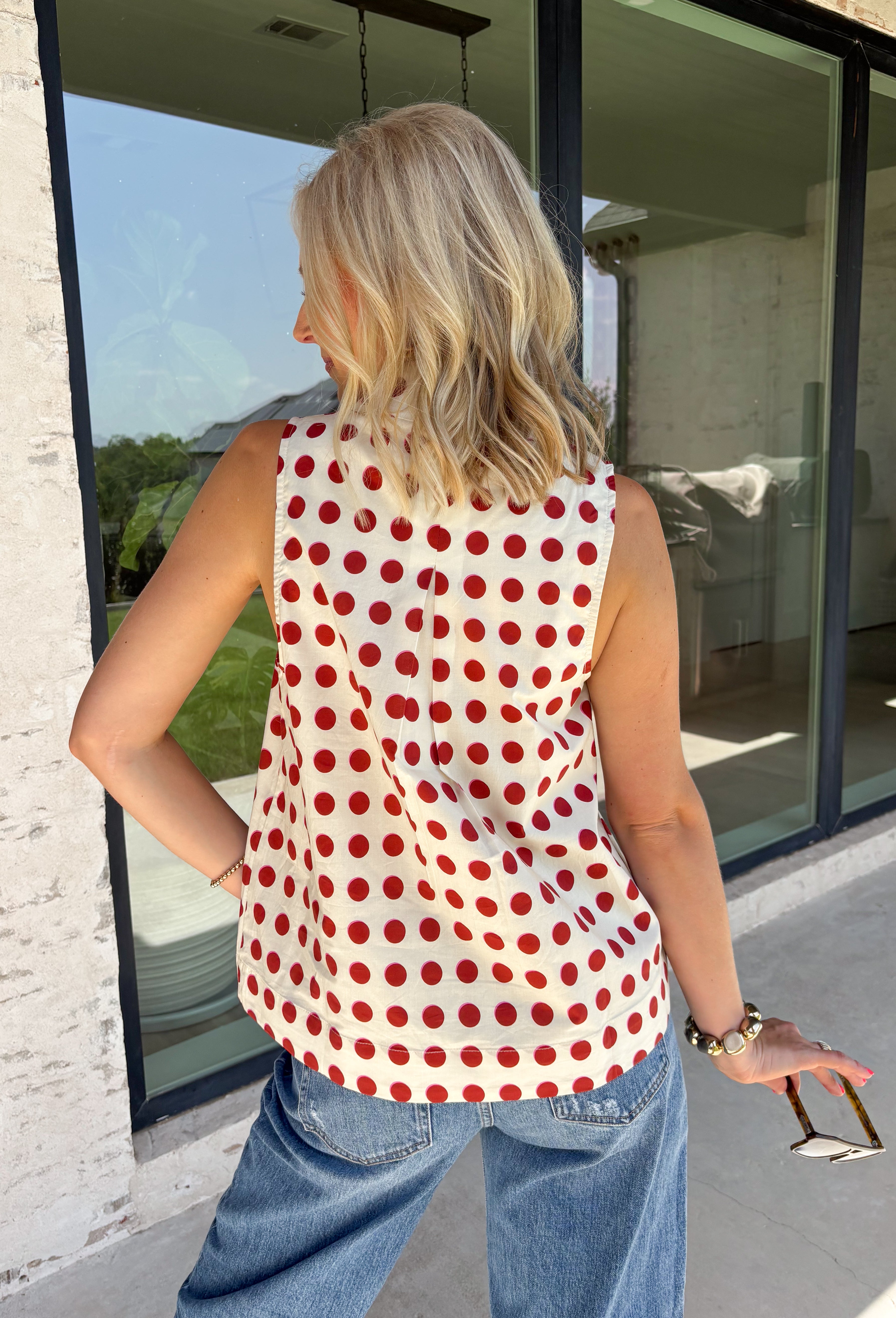 Add a touch of playful charm to your everyday wardrobe with this effortlessly polished sleeveless top from Entro. Featuring a soft ecru backdrop with a rust polka dot print and subtle pops of pink, this lightweight blouse is full of warm seasonal color. The flattering v-neckline keeps the look timeless, while the pleated back detail adds beautiful movement and an easy, flowy fit. 