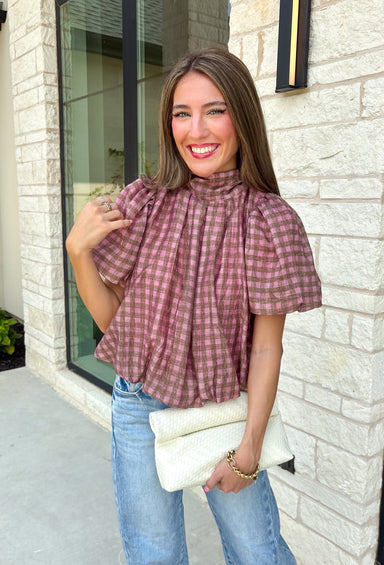 Sweet gingham and thoughtful details make this blouse an instant favorite for the season. Featuring a charming pink and brown gingham print, this lightweight top brings a fresh, feminine touch to your fall wardrobe. The mock neckline with a tie detail at the neck, puff sleeves, and bubble hem create a flattering silhouette that's both polished and comfortable. 