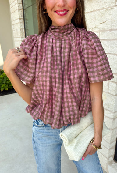 Sweet gingham and thoughtful details make this blouse an instant favorite for the season. Featuring a charming pink and brown gingham print, this lightweight top brings a fresh, feminine touch to your fall wardrobe. The mock neckline with a tie detail at the neck, puff sleeves, and bubble hem create a flattering silhouette that's both polished and comfortable. 