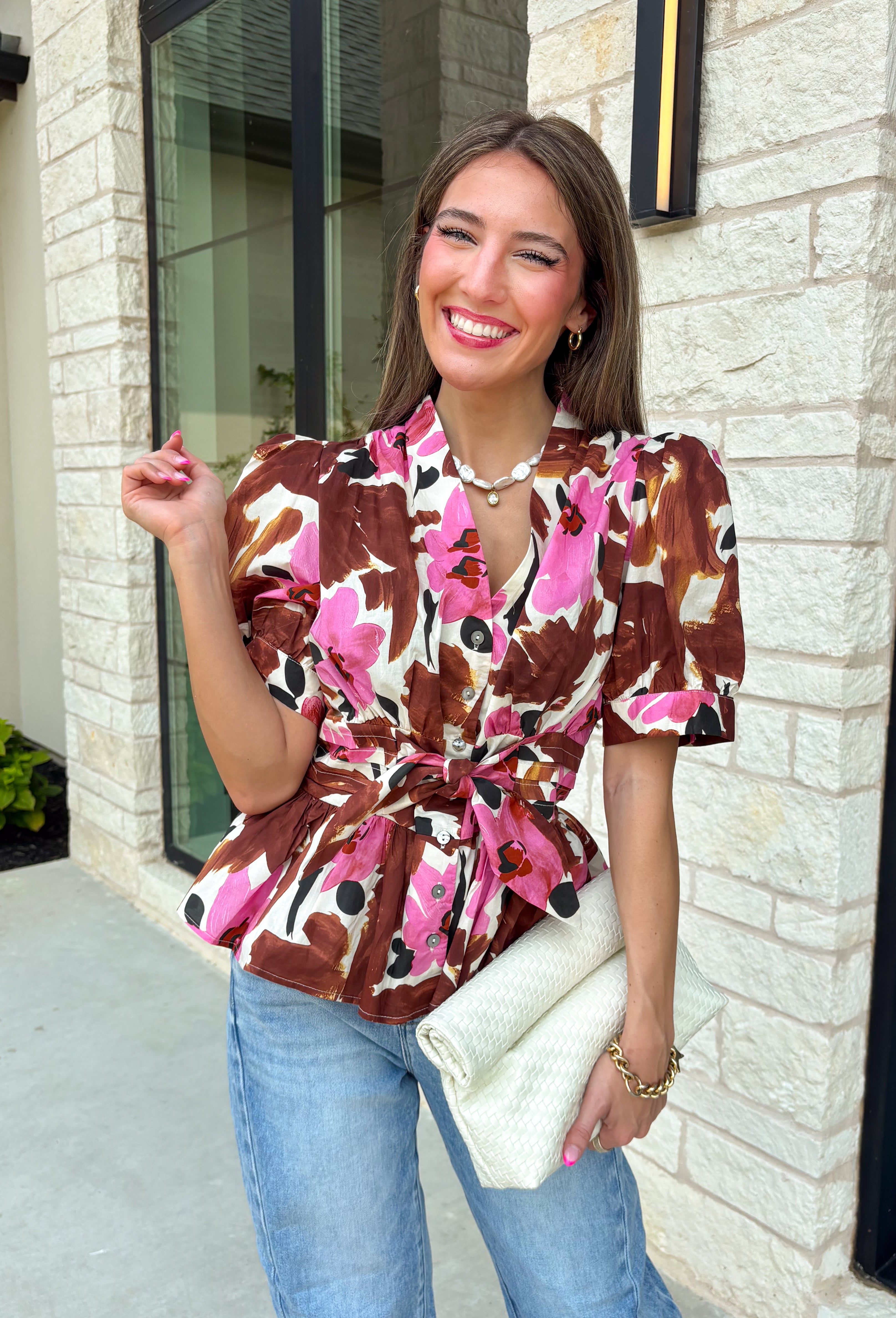 A beautiful floral blouse is one of those pieces you'll reach for all season long, and this one is full of thoughtful details you'll love! Designed with a soft neutral background, this feminine top is adorned with rich brown and pink florals accented by subtle pops of black for the perfect autumn-inspired palette. The flattering self-tie waist creates a customizable silhouette, while the smocked back offers a comfortable fit that moves with you throughout the day.