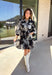 This black floral dress by Entro is a timeless favorite with a touch of charm. Designed with an off-white and gray floral print, it features ¾ puff sleeves, a button-front closure, and a flattering self-tie waist belt. The chest pocket adds a subtle utility touch, while the tiered ruffle hem and side pockets keep the look feminine and functional. This dress is perfect for any special occasion!