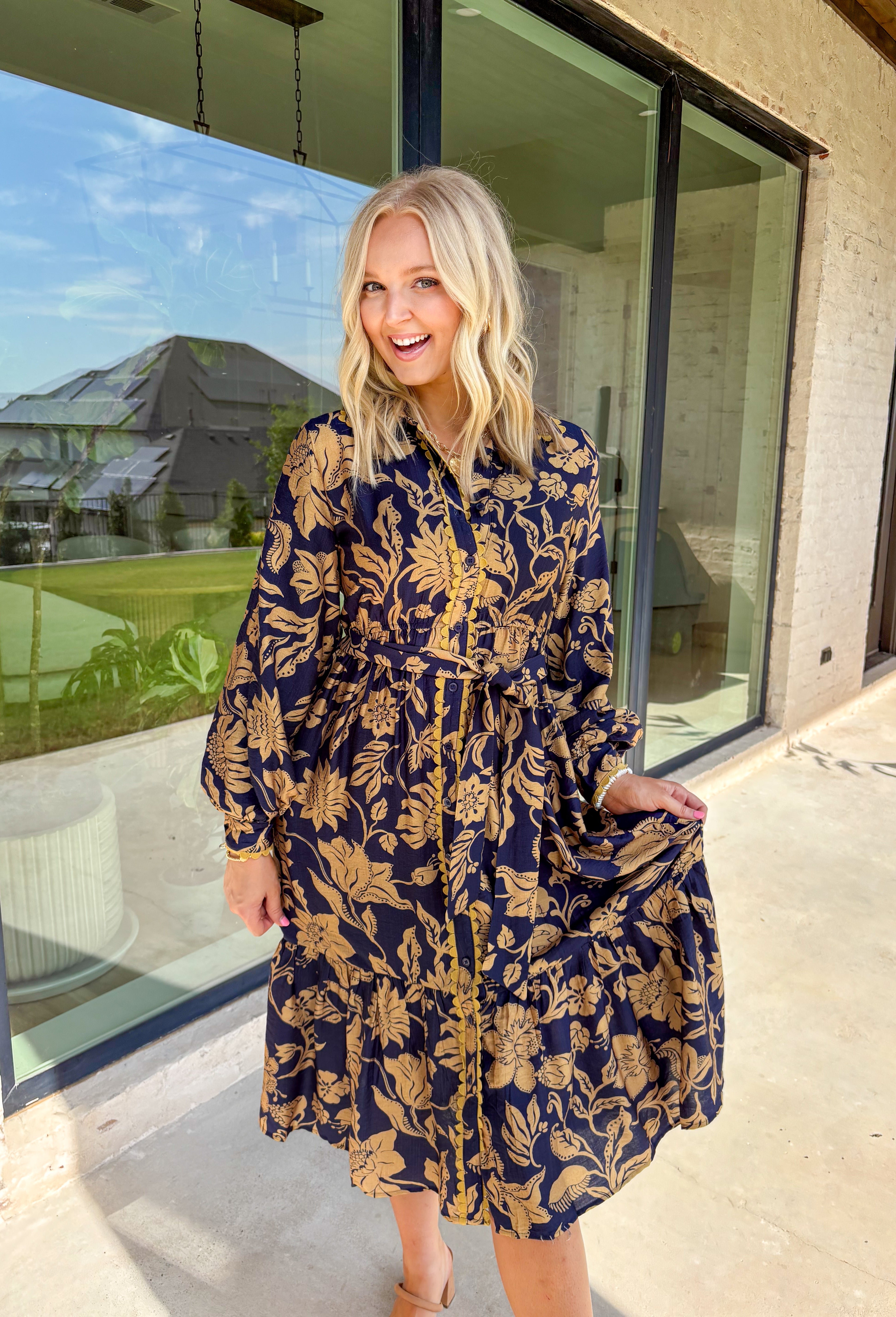 Moody florals meet timeless tailoring in this navy midi dress, patterned with an olive abstract floral print that’s perfect for fall. Scalloped trim along the front softens the look, while the collared neckline and button-down design keep it classic. Balloon sleeves add a hint of drama, and the self-tie waist lets you create a flattering, adjustable fit. Finished with a midi length for versatile styling, this piece is just as ready for weekday wear as it is for weekend outings.