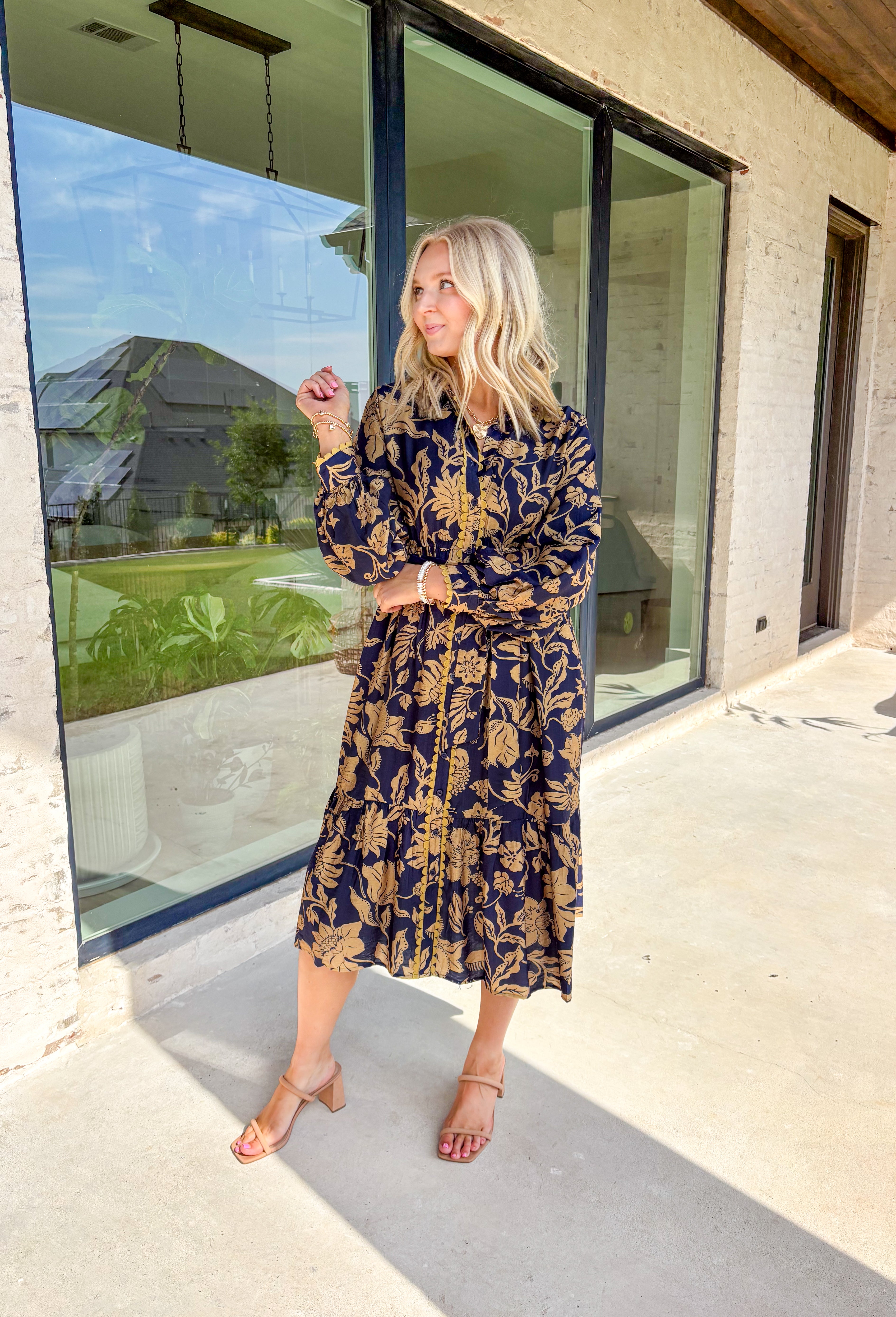 Moody florals meet timeless tailoring in this navy midi dress, patterned with an olive abstract floral print that’s perfect for fall. Scalloped trim along the front softens the look, while the collared neckline and button-down design keep it classic. Balloon sleeves add a hint of drama, and the self-tie waist lets you create a flattering, adjustable fit. Finished with a midi length for versatile styling, this piece is just as ready for weekday wear as it is for weekend outings.