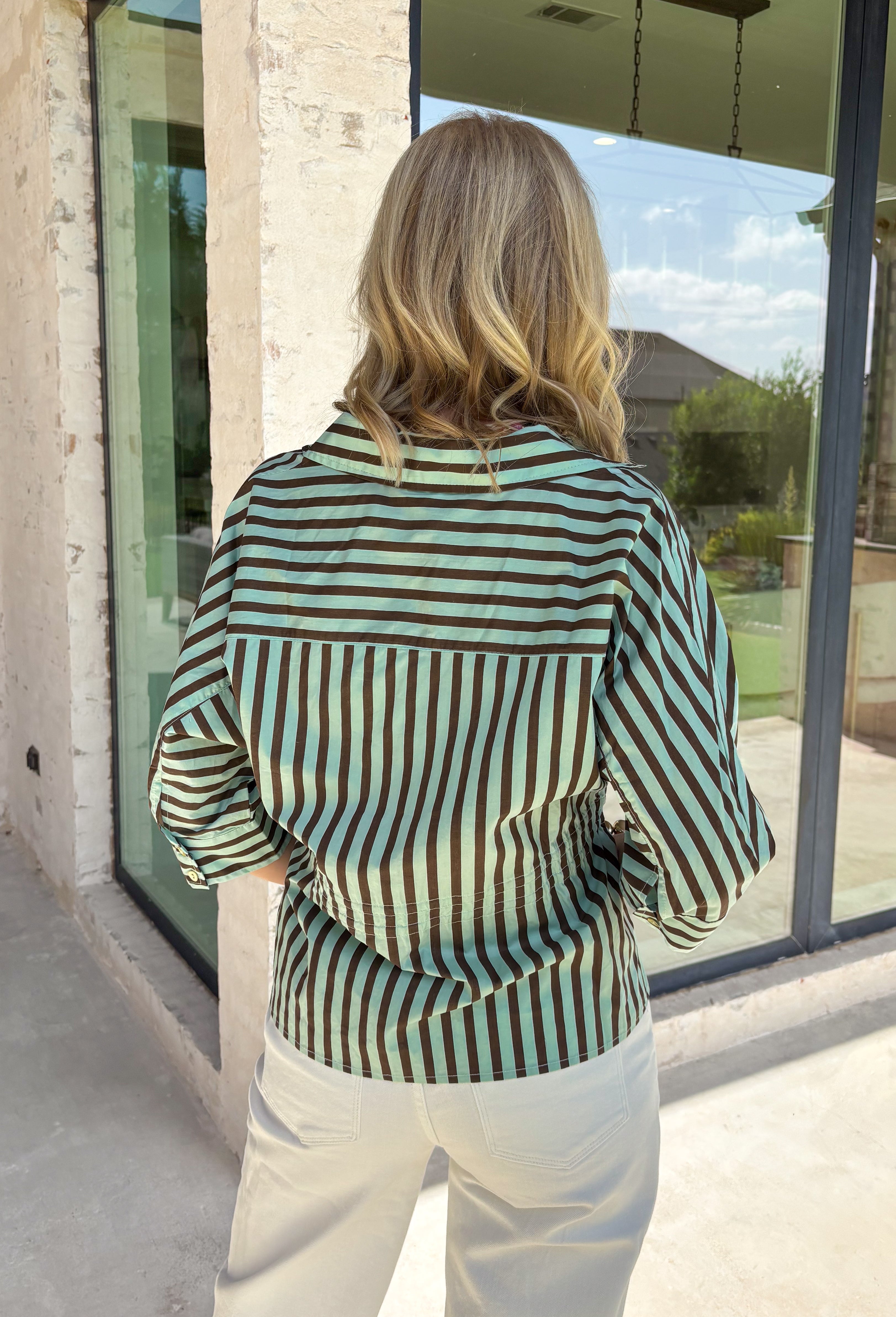 Fresh colors and flattering details make this striped blouse an easy favorite for the season. Designed with soft mint and brown stripes, this effortlessly polished top features a classic v-neckline and button-front design for timeless appeal. The adjustable drawstring waist creates a flattering, customizable fit, while the ¾-length sleeves with button cuffs add a refined finishing touch. Crafted from breathable cotton, this versatile blouse transitions seamlessly from workdays to weekend outings.