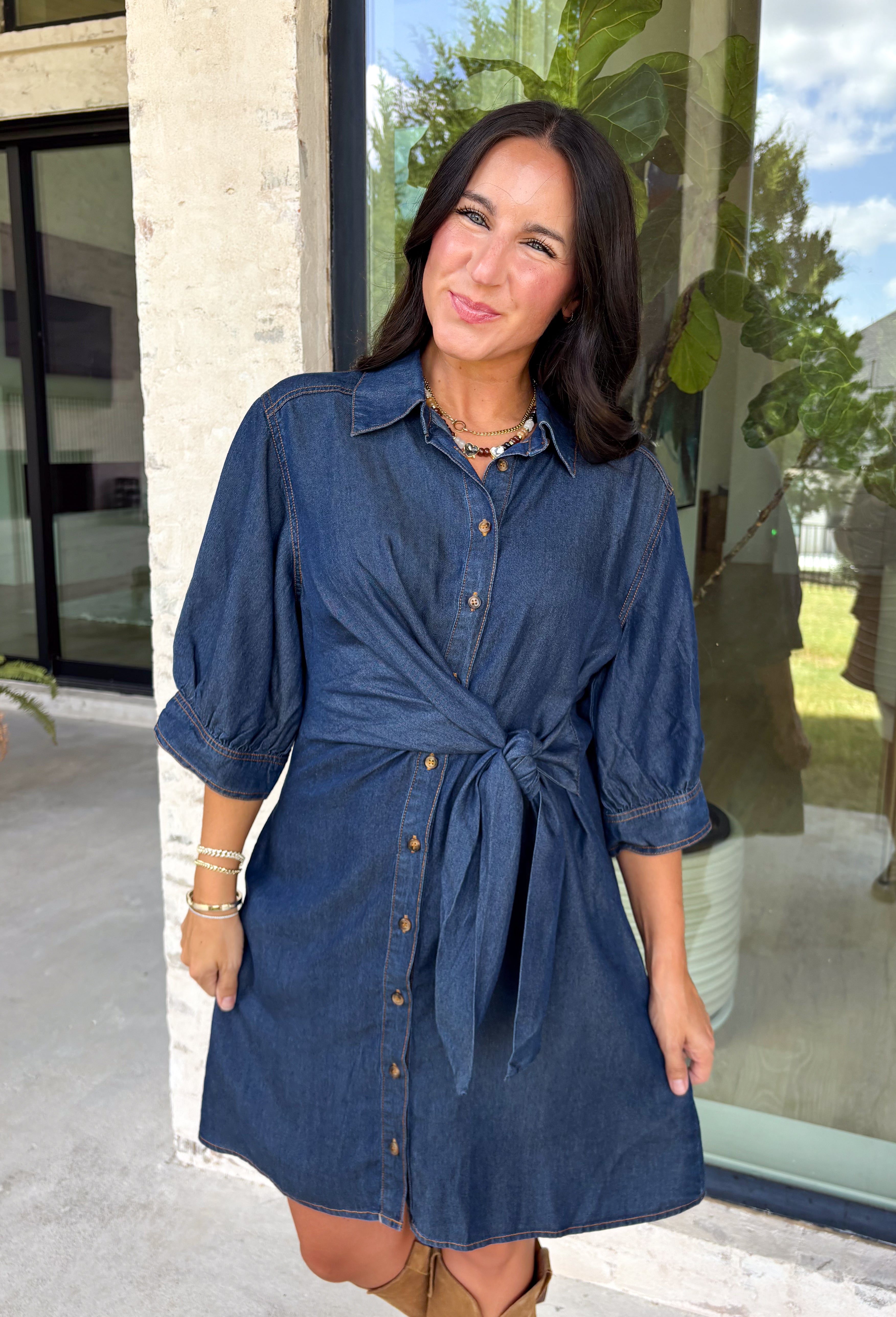 A timeless denim dress is always in style, and this lightweight beauty from Entro is one you'll wear on repeat. Crafted from soft medium wash tencel denim, this effortlessly flattering dress features a classic button-front design, a feminine v-neckline, and a matching self-tie waist that creates the perfect customizable fit. The ¾ length sleeves with button cuffs add a polished touch, while side pockets make it as practical as it is stylish. 