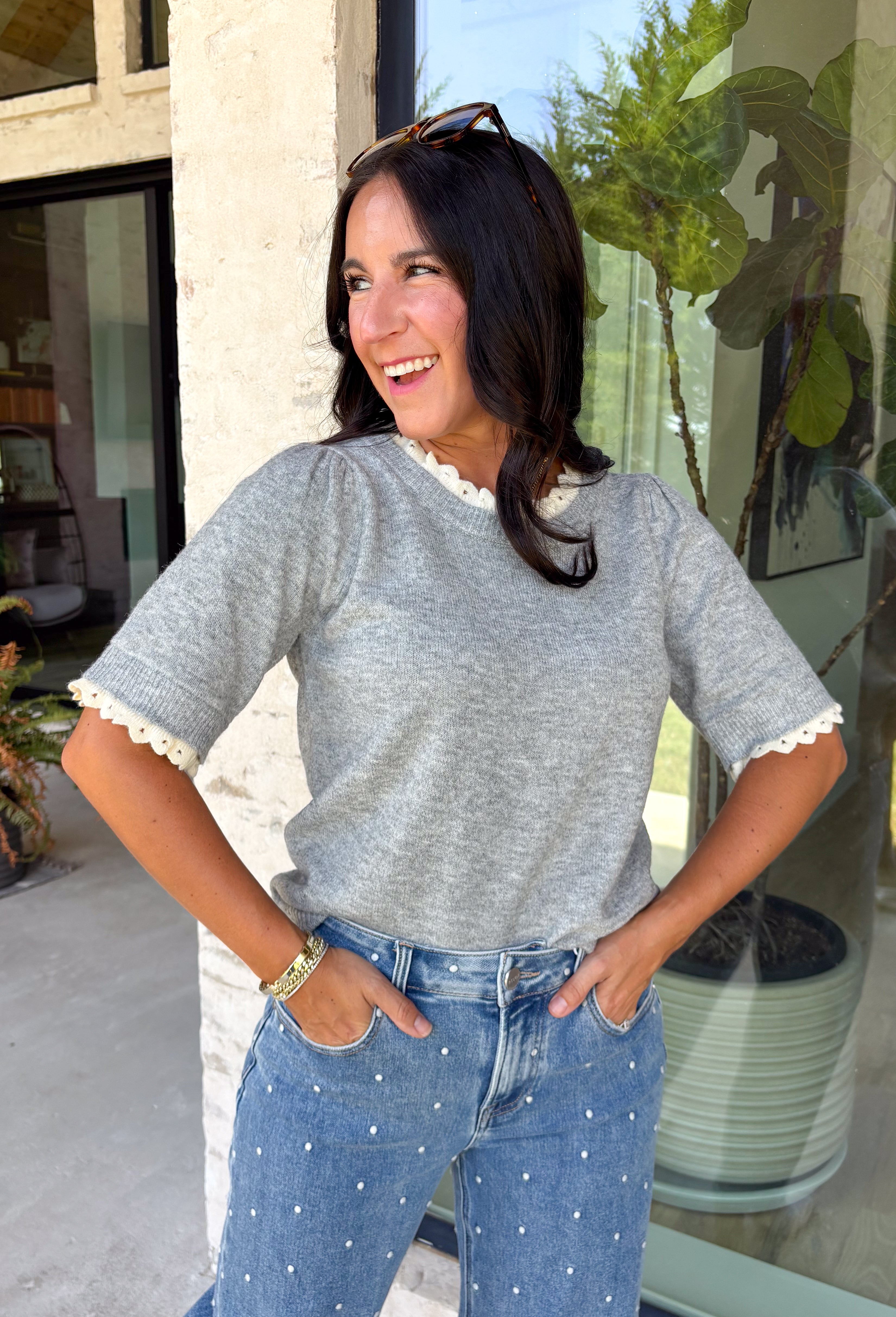 This grey short sleeve sweater is the perfect blend of cozy and classic for the fall season! The soft knit is beautifully finished with ivory scalloped trim along the neckline and sleeves, creating the look of an effortlessly layered outfit without any extra bulk. Its timeless silhouette makes it easy to style for work, weekend outings, or dinner with friends, while the lightweight knit is perfect for those crisp autumn days. 