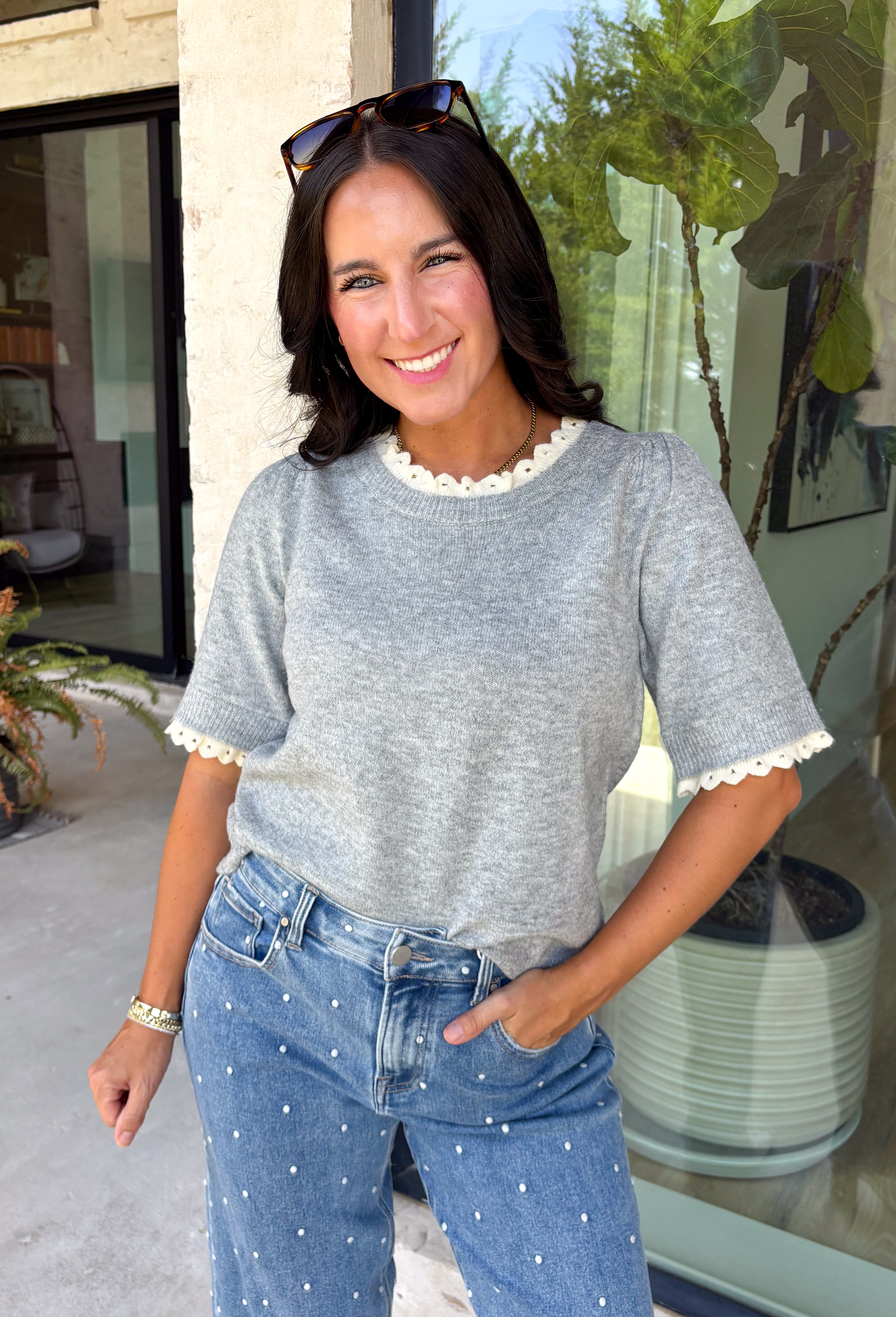 This grey short sleeve sweater is the perfect blend of cozy and classic for the fall season! The soft knit is beautifully finished with ivory scalloped trim along the neckline and sleeves, creating the look of an effortlessly layered outfit without any extra bulk. Its timeless silhouette makes it easy to style for work, weekend outings, or dinner with friends, while the lightweight knit is perfect for those crisp autumn days. 