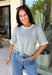 This grey short sleeve sweater is the perfect blend of cozy and classic for the fall season! The soft knit is beautifully finished with ivory scalloped trim along the neckline and sleeves, creating the look of an effortlessly layered outfit without any extra bulk. Its timeless silhouette makes it easy to style for work, weekend outings, or dinner with friends, while the lightweight knit is perfect for those crisp autumn days. 