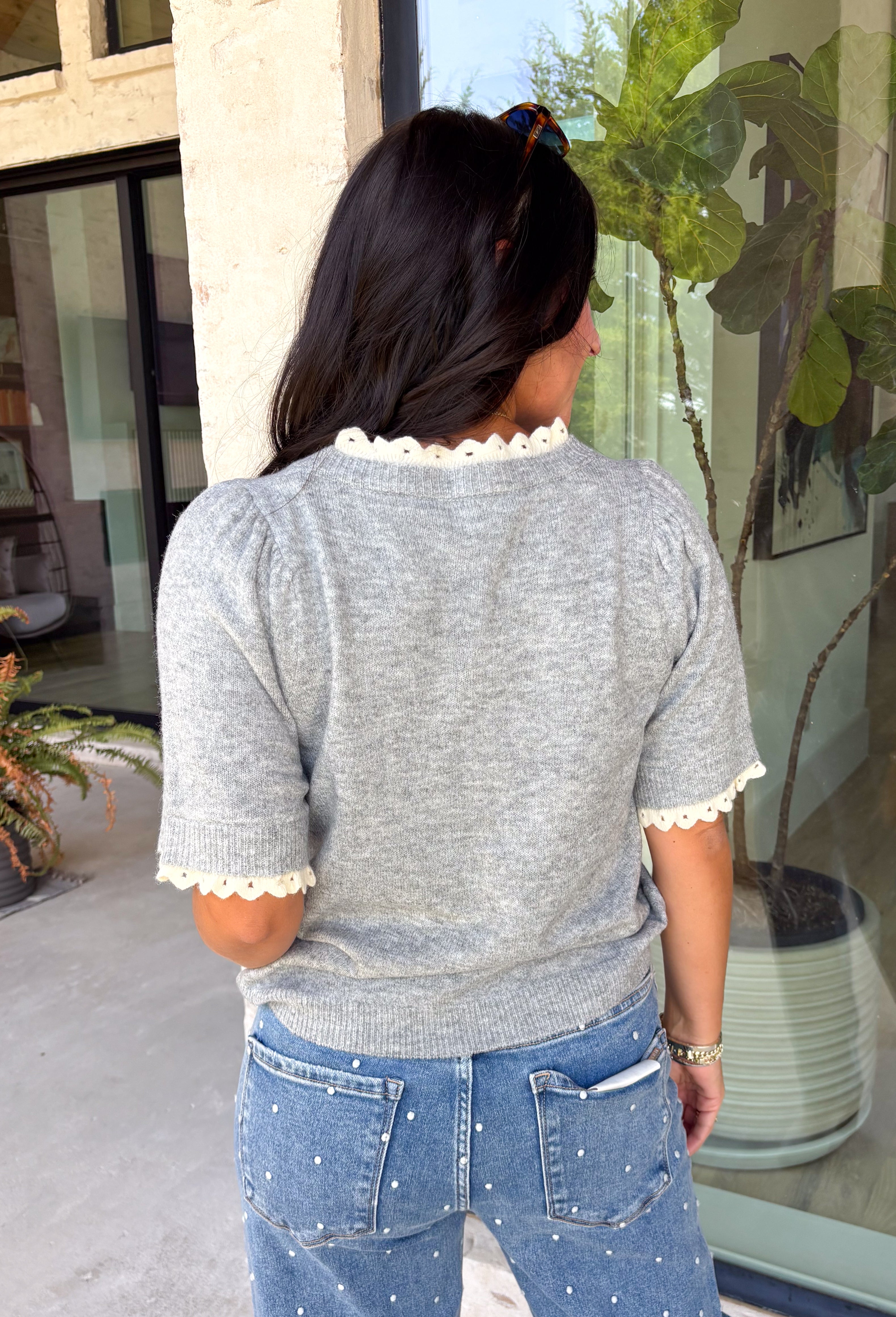 This grey short sleeve sweater is the perfect blend of cozy and classic for the fall season! The soft knit is beautifully finished with ivory scalloped trim along the neckline and sleeves, creating the look of an effortlessly layered outfit without any extra bulk. Its timeless silhouette makes it easy to style for work, weekend outings, or dinner with friends, while the lightweight knit is perfect for those crisp autumn days. 