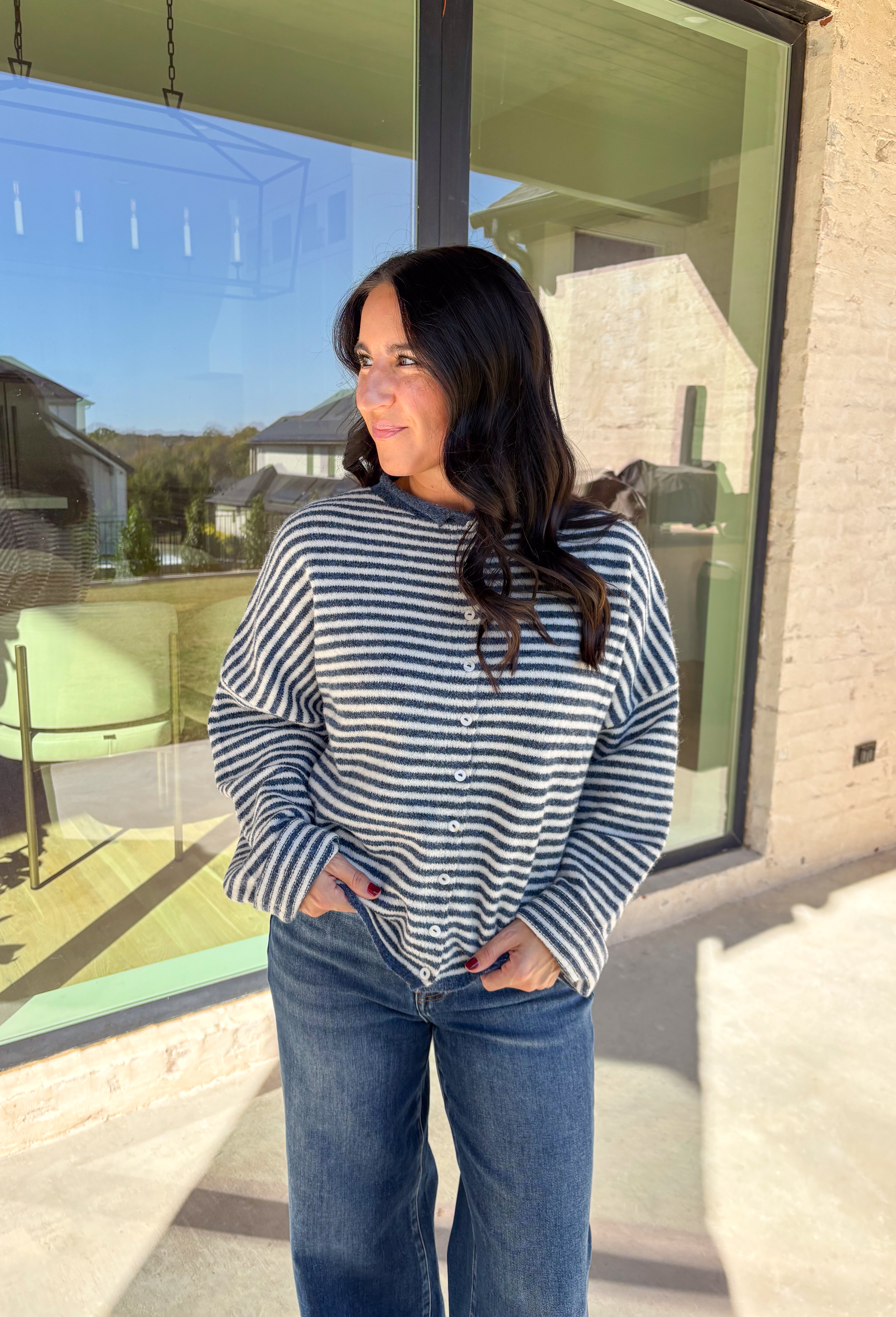 Classic stripes meet cozy comfort in this navy and white button-down cardigan by Things Between. Designed in a soft knit with a relaxed fit, this timeless piece brings effortless warmth to your winter wardrobe. The simple stripe pattern adds a touch of everyday charm, making it easy to style for layering through the colder months.