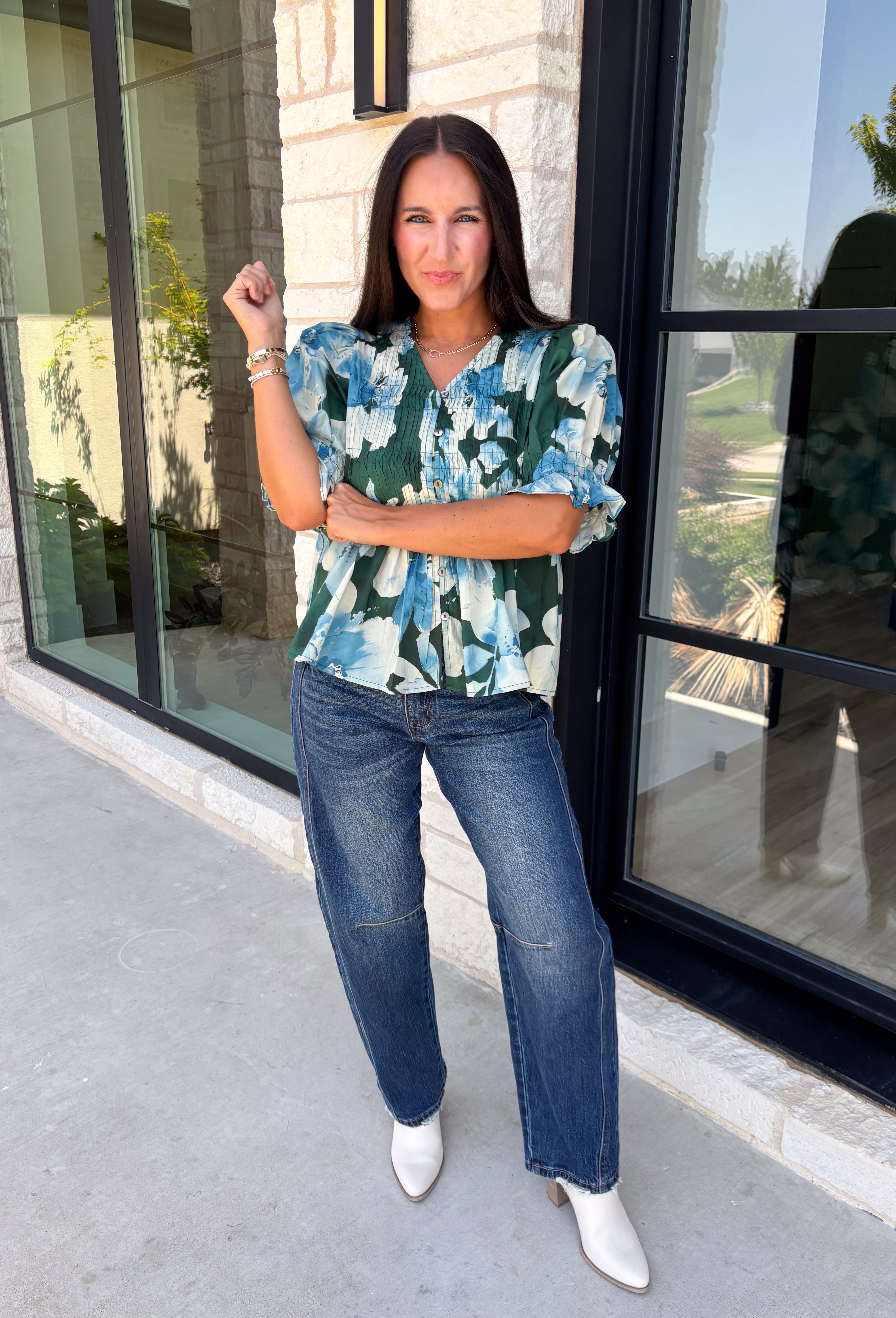 Bring a fresh take on fall florals to your wardrobe with this beautiful hunter green top. Featuring a delicate blue and off white floral print, this timeless top is perfect for everything from office days to weekend outings. The pintuck detailing along the front adds an elevated touch, while the button front and short puff sleeves create a feminine silhouette you'll love season after season. 