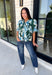 Bring a fresh take on fall florals to your wardrobe with this beautiful hunter green top. Featuring a delicate blue and off white floral print, this timeless top is perfect for everything from office days to weekend outings. The pintuck detailing along the front adds an elevated touch, while the button front and short puff sleeves create a feminine silhouette you'll love season after season. 