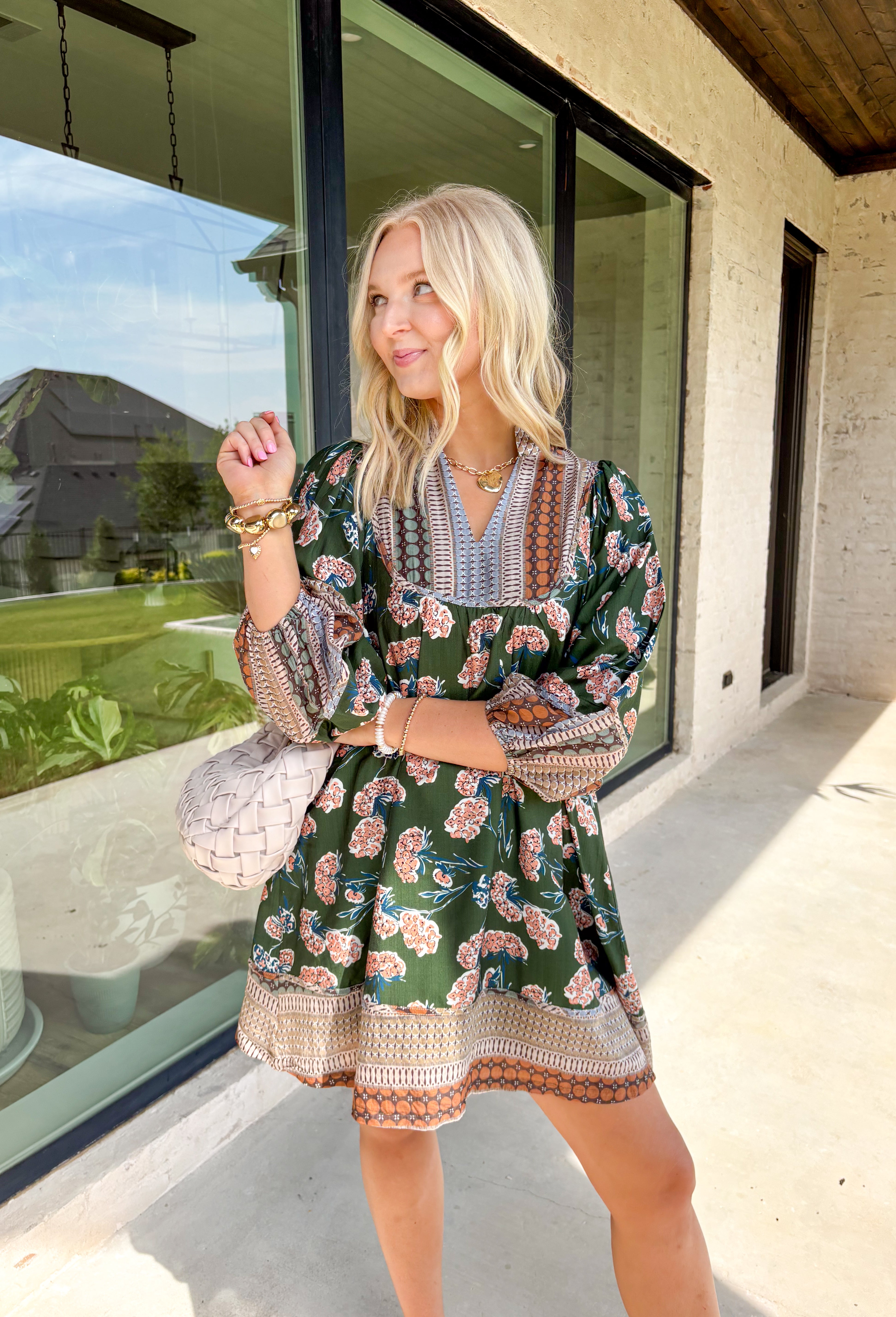 Bring a rich fall palette into your wardrobe with this dark green dress, designed with a mix of seasonal florals. Trimmed in an abstract print along the neckline, hemline, and sleeves, it has an artisan-inspired finish that feels unique and thoughtful. The elastic cuff sleeves add comfort and a touch of volume, while the flowy silhouette and full lining keep it easy to wear from day to night. Accented with shades of brown, this dress is a cozy yet elevated choice for the season.