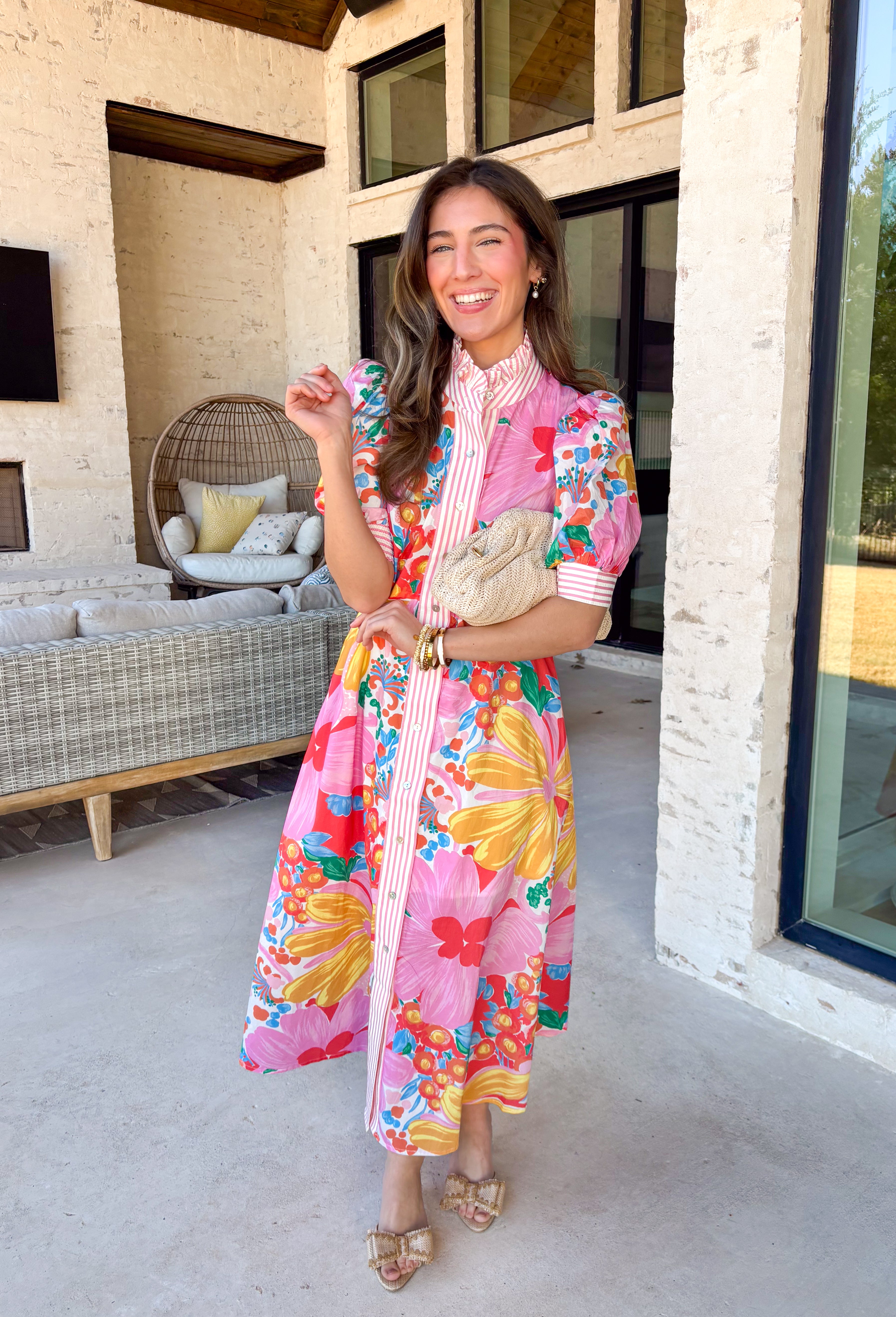 Bright, joyful, and bursting with spring color, this white short sleeve button-down dress by Entro is a total showstopper. Featuring a bold floral print in pink, red, blue, yellow, green, and orange, it brings instant happy vibes to your wardrobe. The ruffle neckline is trimmed with pink and white stripes for a fun pop of contrast, with matching stripe detail running down the front and along the sleeve cuffs. Smocking at the back of the sleeves adds comfort and shape, while side pockets and a lining make it