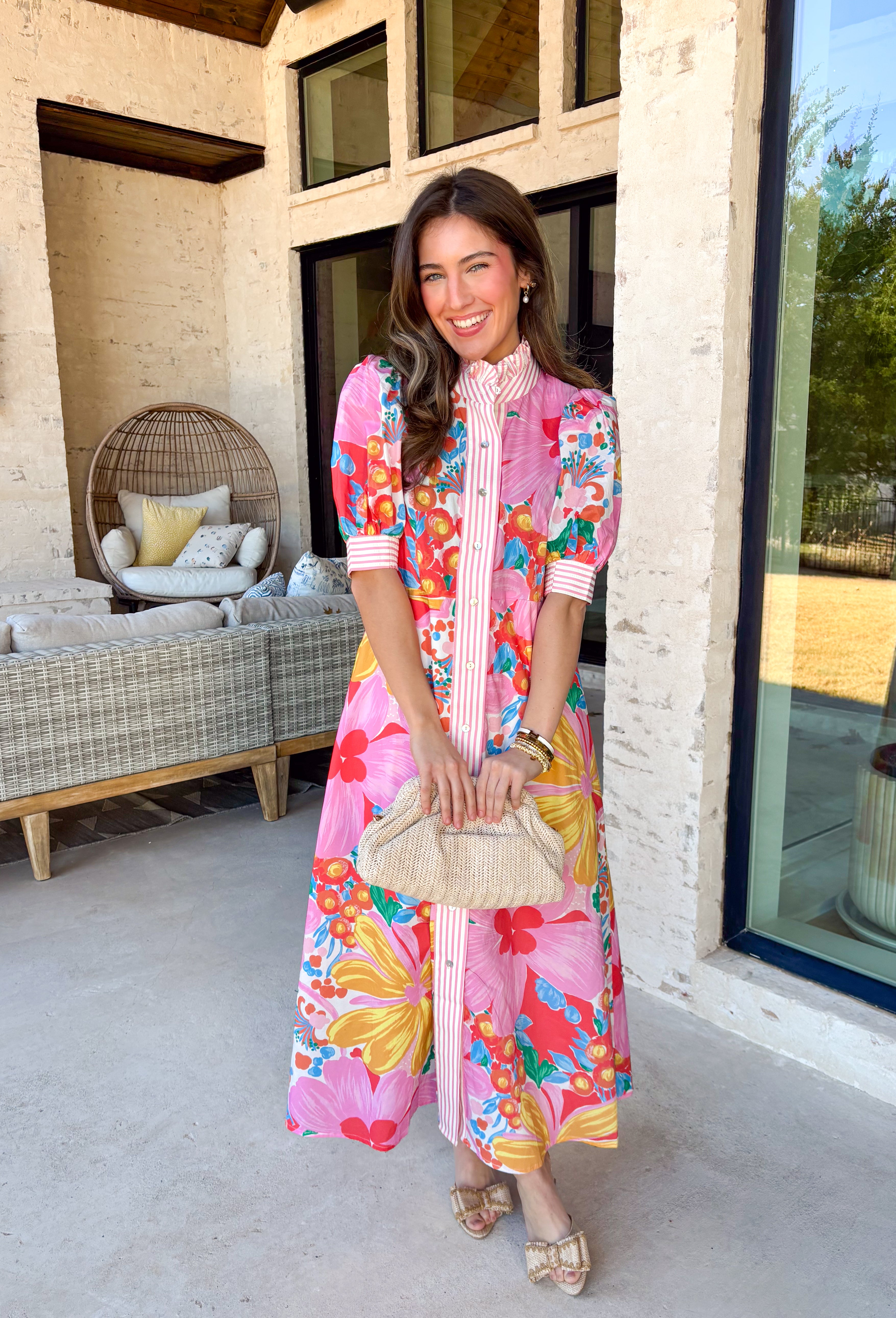 Bright, joyful, and bursting with spring color, this white short sleeve button-down dress by Entro is a total showstopper. Featuring a bold floral print in pink, red, blue, yellow, green, and orange, it brings instant happy vibes to your wardrobe. The ruffle neckline is trimmed with pink and white stripes for a fun pop of contrast, with matching stripe detail running down the front and along the sleeve cuffs. Smocking at the back of the sleeves adds comfort and shape, while side pockets and a lining make it