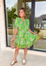 Bring a burst of sunshine to your spring wardrobe with this lime green dress. The lively floral print features playful pops of lilac, green, and white, while the contrasting hem in green, mustard, and white adds a fun, unexpected twist. The button-down front and self-tie belt create a flattering, adjustable fit, and the lightweight fabric keeps it breezy for warm spring days. Whether you’re headed to brunch or strolling the farmers’ market, this dress is all about easy, cheerful style.